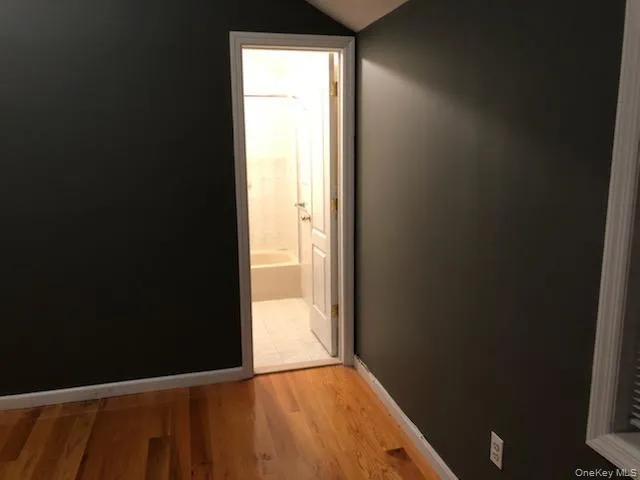 Corridor featuring light wood-style floors and vaulted ceiling Corridor featuring light wood-style floors and vaulted ceiling