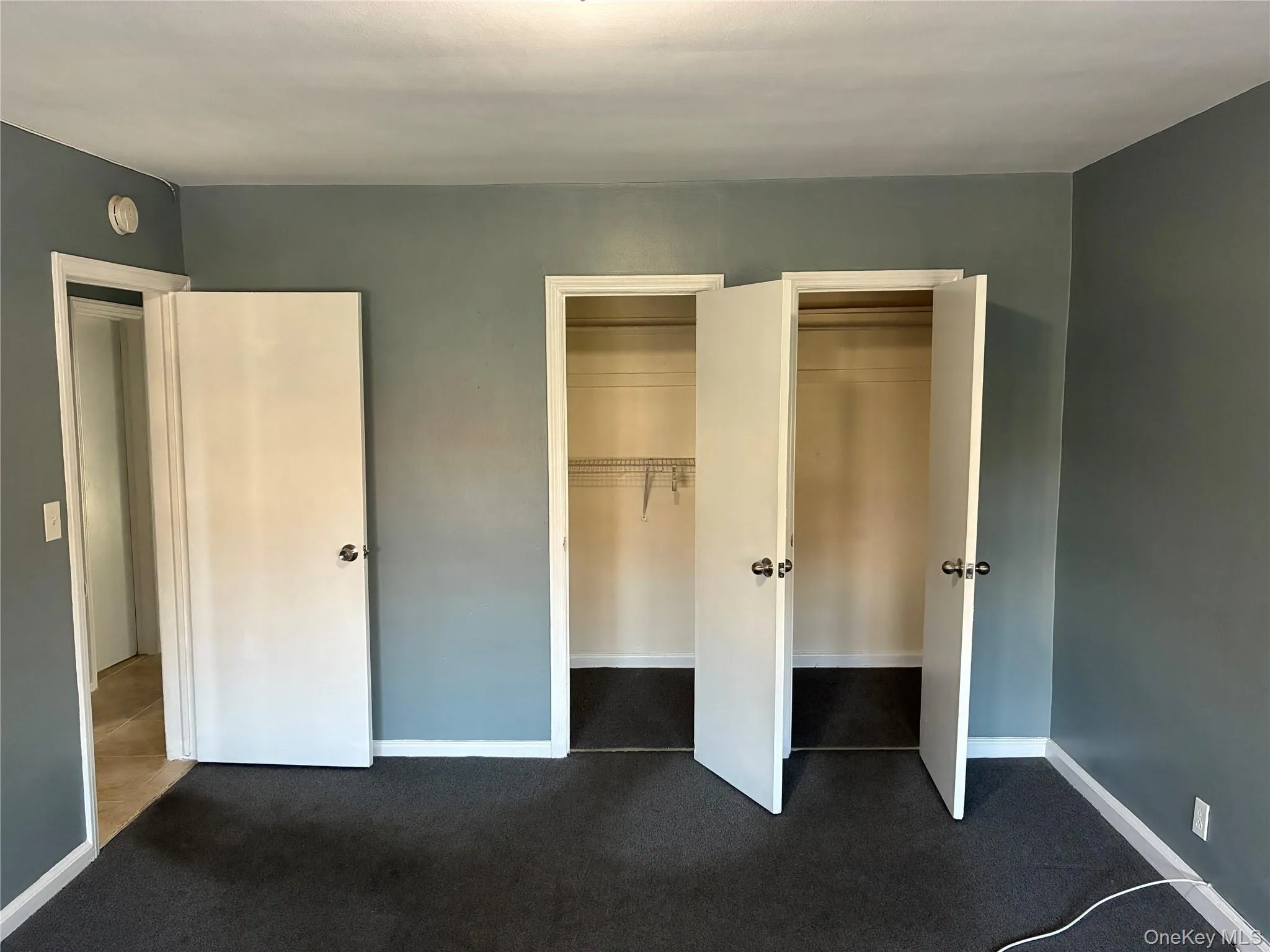 Unfurnished bedroom with multiple closets and dark carpet Unfurnished bedroom with multiple closets and dark carpet