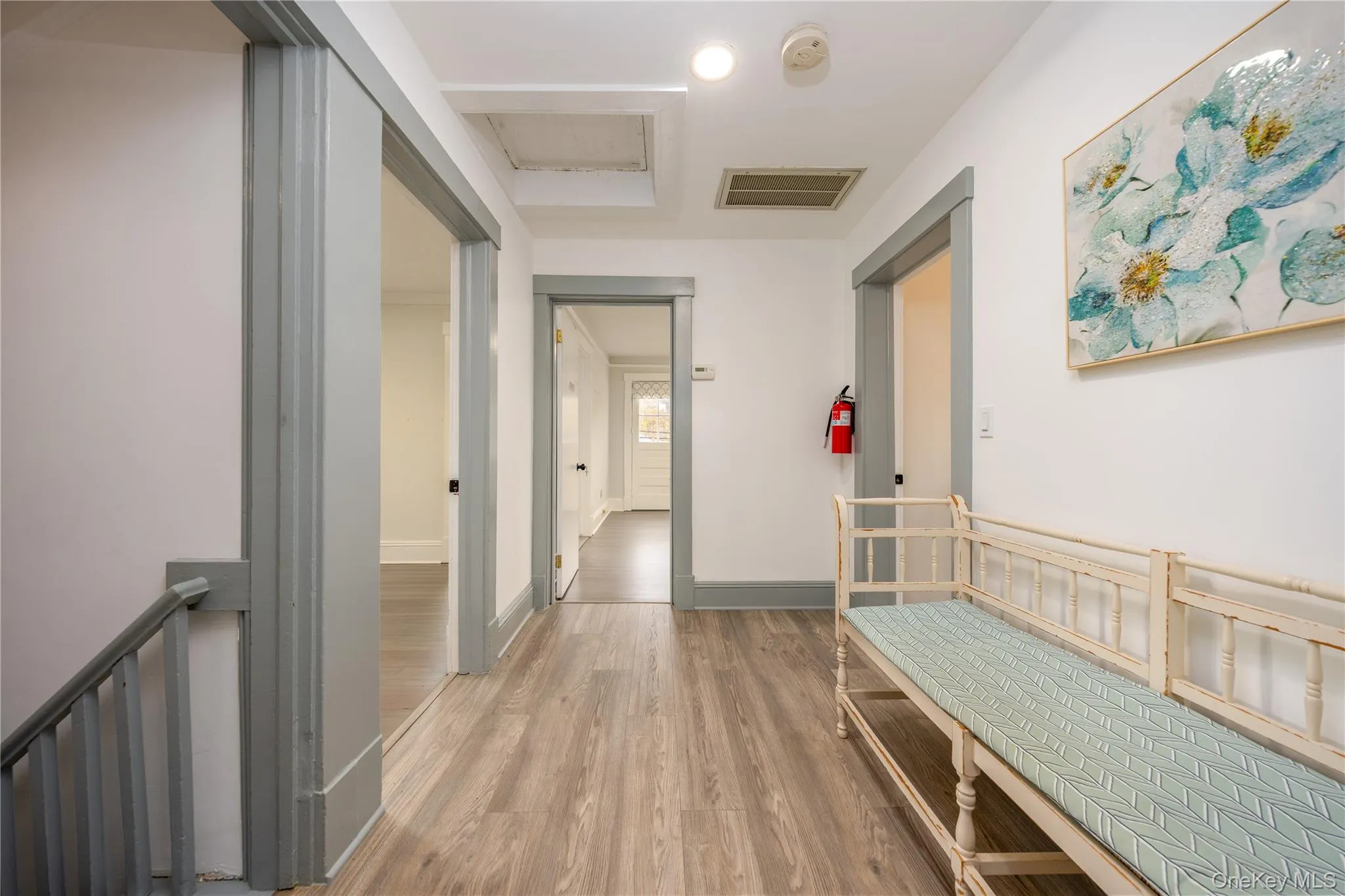 Corridor featuring light wood-type flooring, an upstairs landing, and attic access Corridor featuring light wood-type flooring, an upstairs landing, and attic access