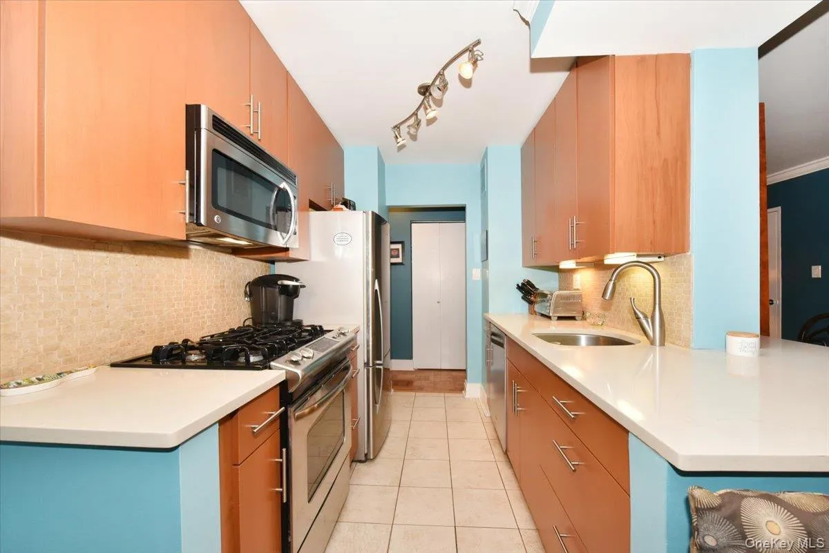 Kitchen with stainless steel appliances, tasteful backsplash, light tile patterned floors, light stone counters, and modern cabinets Kitchen with stainless steel appliances, tasteful backsplash, light tile patterned floors, light stone counters, and modern cabinets