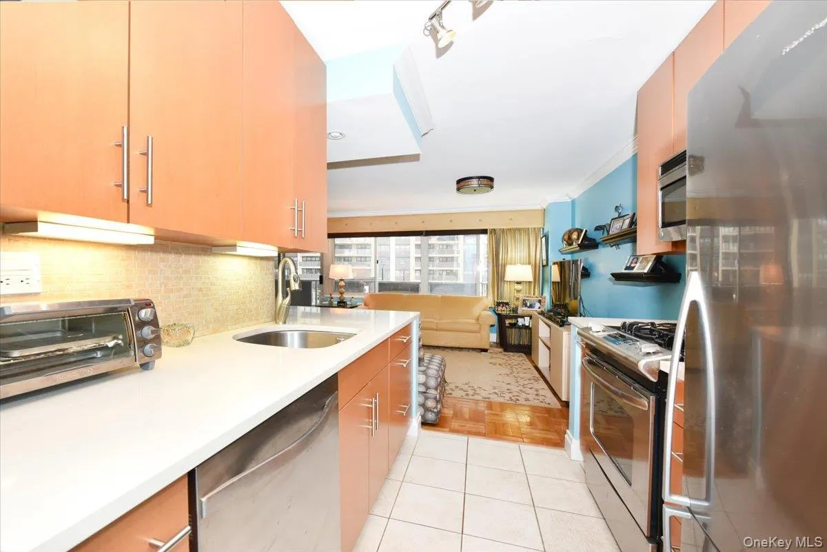 Kitchen with stainless steel appliances, light tile patterned floors, backsplash, ornamental molding, and open floor plan Kitchen with stainless steel appliances, light tile patterned floors, backsplash, ornamental molding, and open floor plan