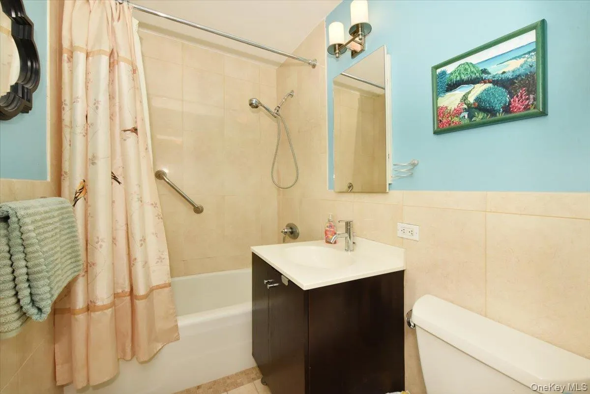 Full bath featuring shower / bath combo with shower curtain, vanity, and tile walls Full bath featuring shower / bath combo with shower curtain, vanity, and tile walls