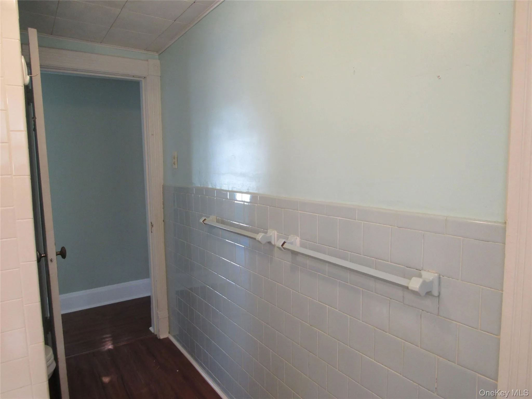 Bathrrom with tile walls, a wainscoted wall, and dark wood-type flooring Bathrrom with tile walls, a wainscoted wall, and dark wood-type flooring