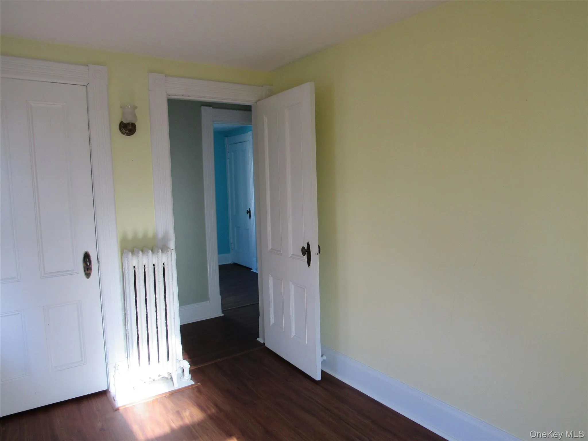 Bedroom #4 with radiator heating unit and dark wood-style flooring Bedroom #4 with radiator heating unit and dark wood-style flooring