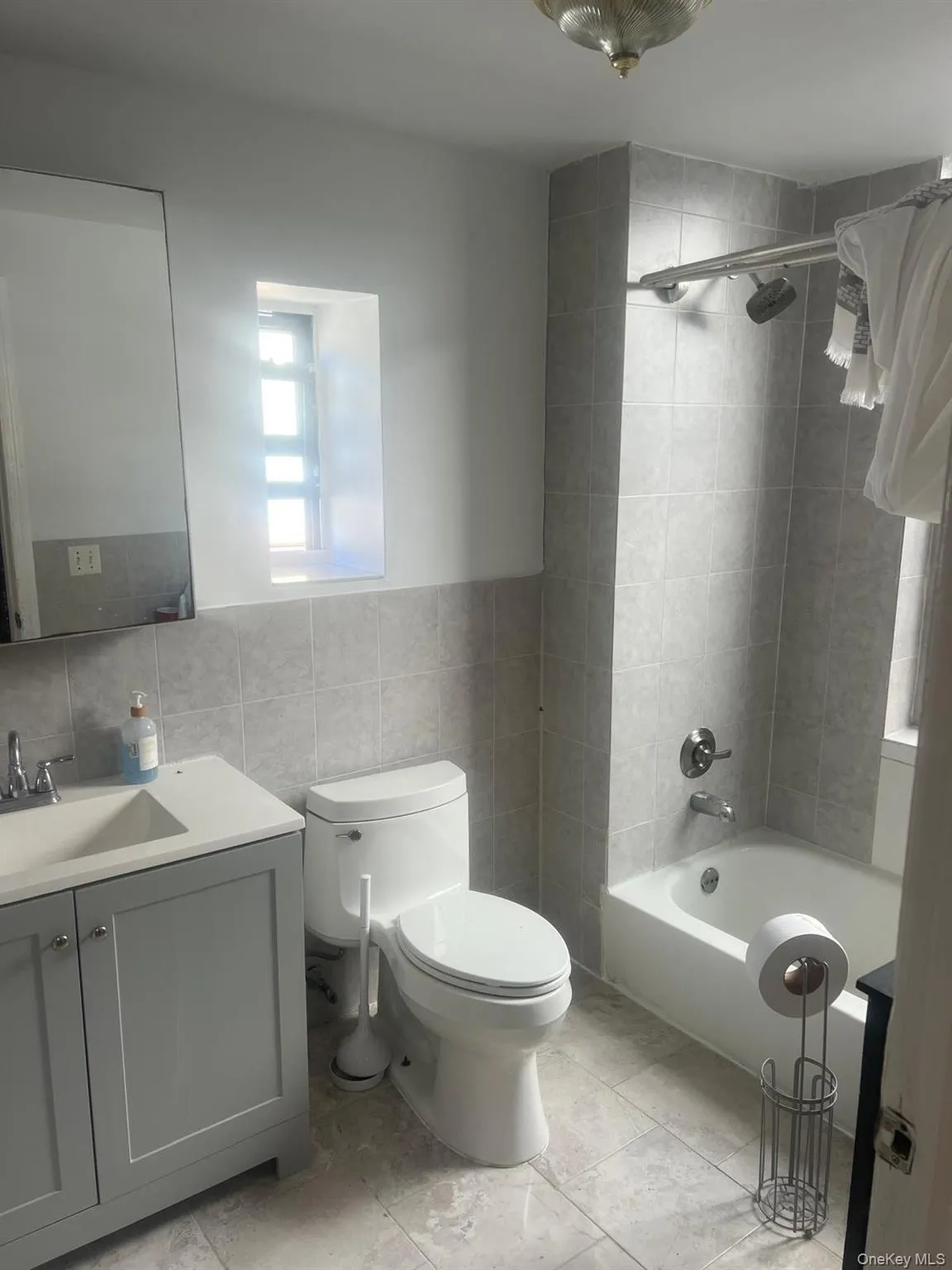 Bathroom featuring vanity, bathtub / shower combination, and tile walls Bathroom featuring vanity, bathtub / shower combination, and tile walls