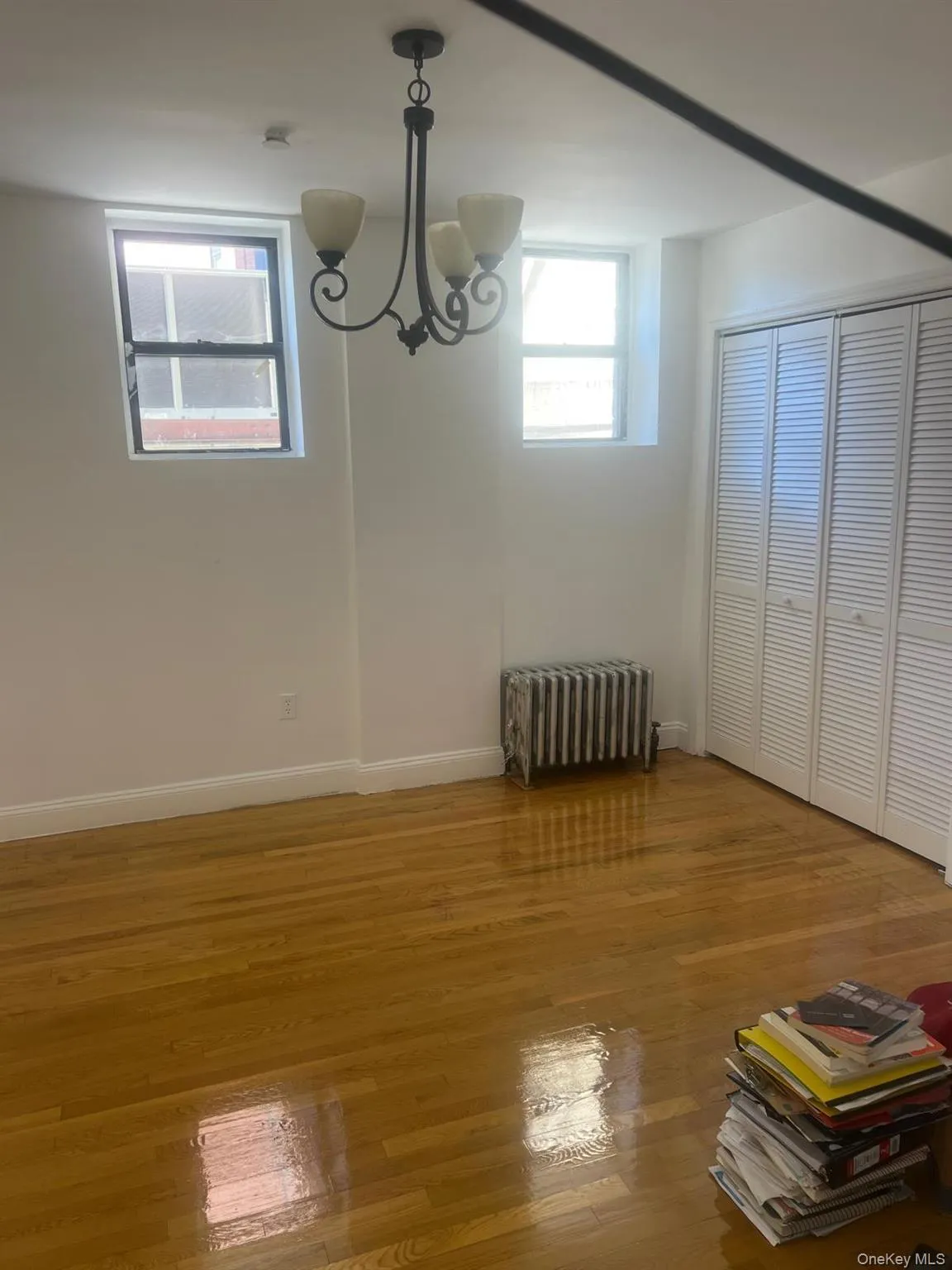 Unfurnished dining area with radiator heating unit, plenty of natural light, a chandelier, and light wood-style flooring Unfurnished dining area with radiator heating unit, plenty of natural light, a chandelier, and light wood-style flooring