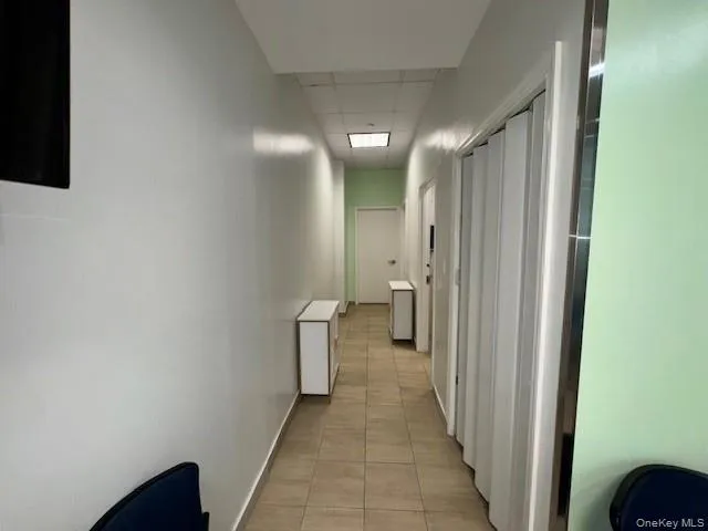 Hallway with a paneled ceiling and light tile patterned floors Hallway with a paneled ceiling and light tile patterned floors