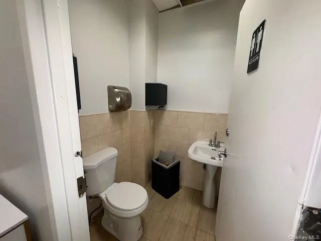 Half bathroom with tile walls, a wainscoted wall, and light tile patterned flooring Half bathroom with tile walls, a wainscoted wall, and light tile patterned flooring