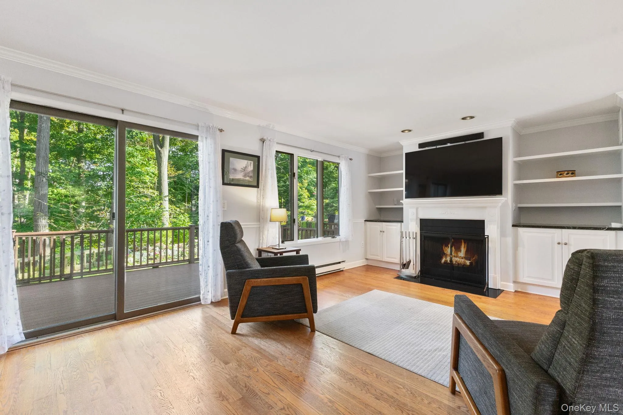 The living room features wood floors, a wood-burning fireplace, and custom built-in shelves and cabinetry. The living room features wood floors, a wood-burning fireplace, and custom built-in shelves and cabinetry.