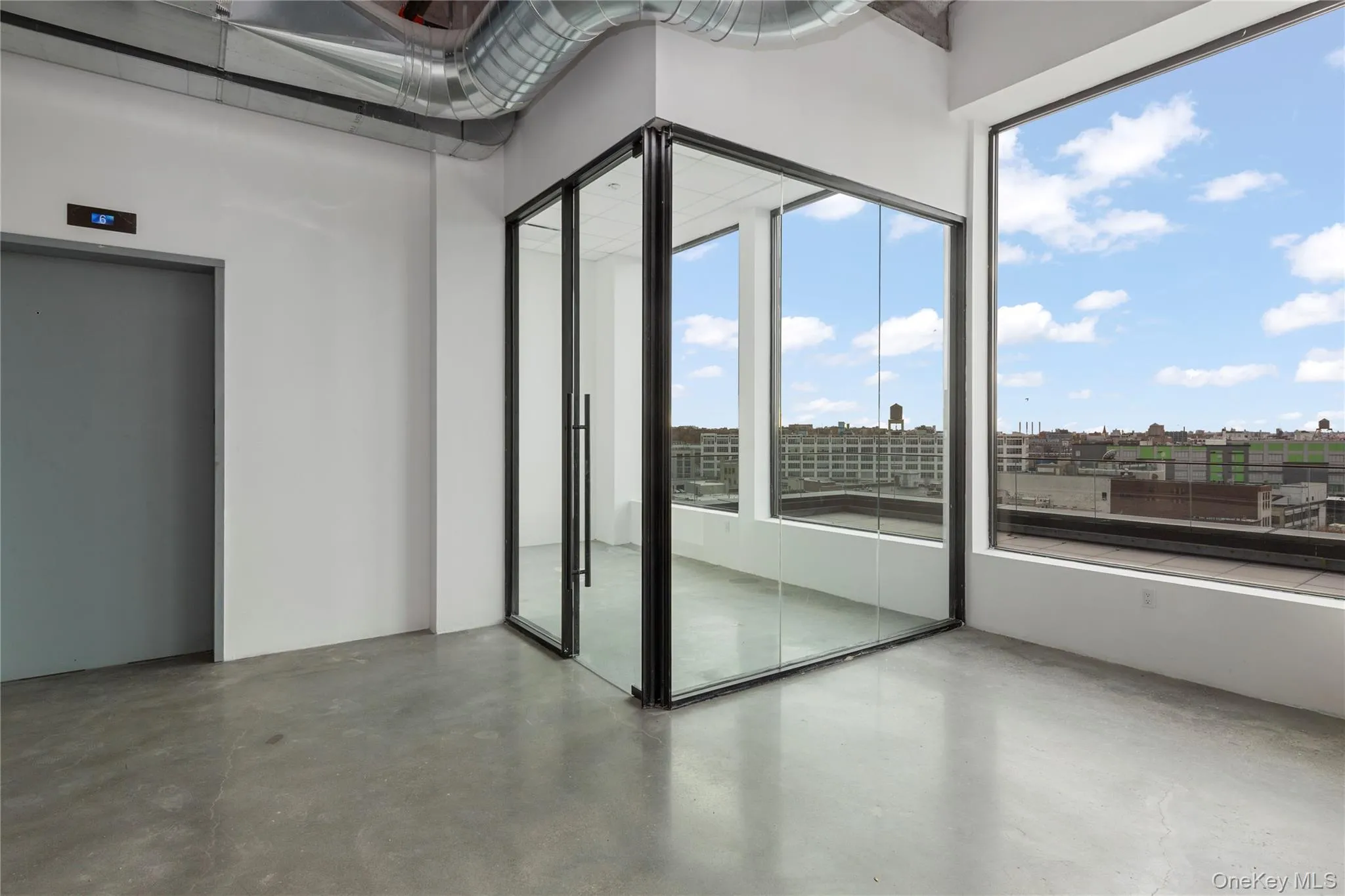 Unfurnished room with elevator, finished concrete flooring, and a city view Unfurnished room with elevator, finished concrete flooring, and a city view