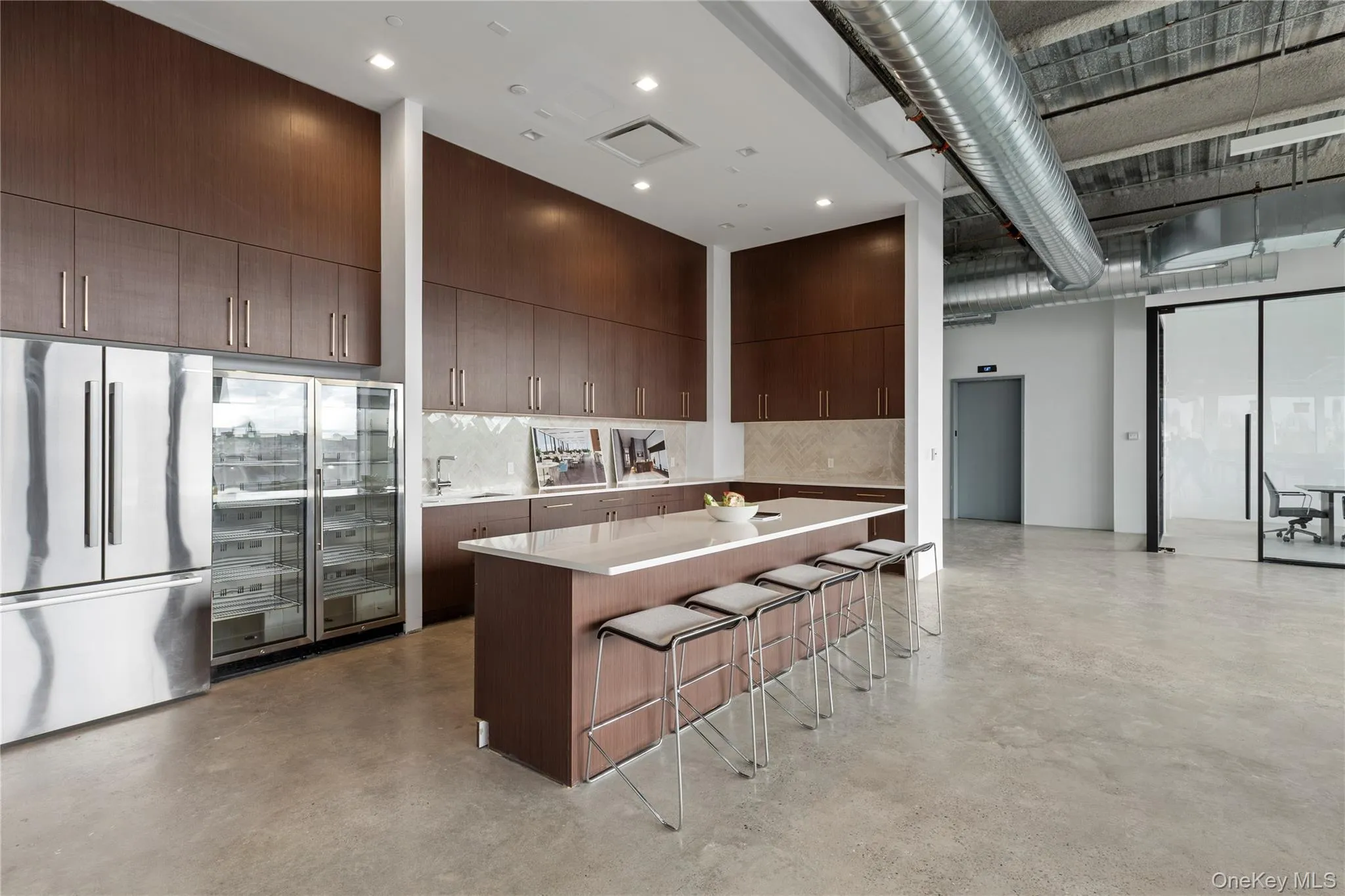 Kitchen featuring freestanding refrigerator, backsplash, a kitchen bar, a large island, and a towering ceiling Kitchen featuring freestanding refrigerator, backsplash, a kitchen bar, a large island, and a towering ceiling