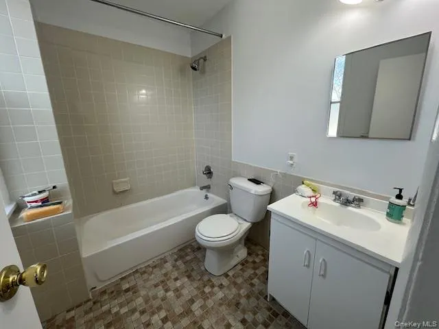 Full bathroom with vanity, shower combination, tile walls, and wainscoting Full bathroom with vanity, shower combination, tile walls, and wainscoting