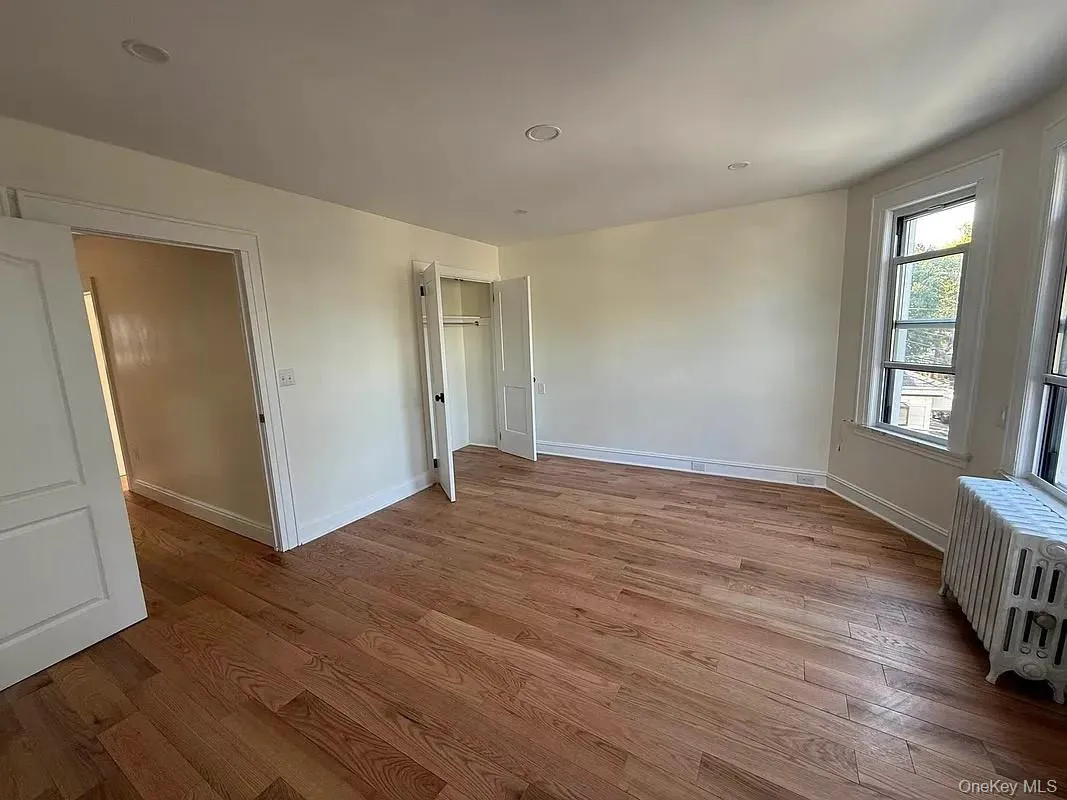 Unfurnished bedroom with radiator, light wood-style floors, a closet, and recessed lighting Unfurnished bedroom with radiator, light wood-style floors, a closet, and recessed lighting
