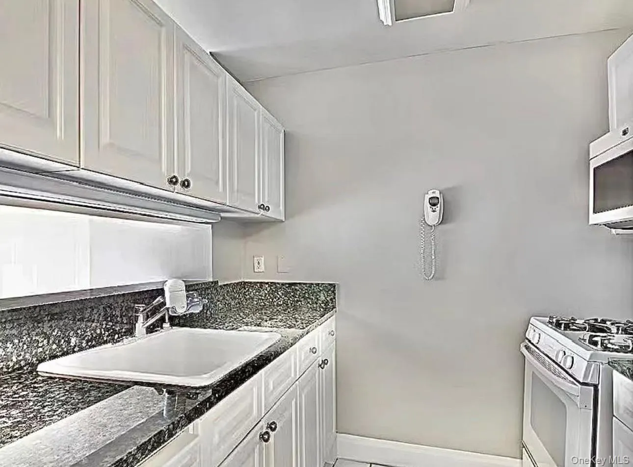 Kitchen featuring white range with gas stovetop, white cabinets, and stainless steel microwave Kitchen featuring white range with gas stovetop, white cabinets, and stainless steel microwave