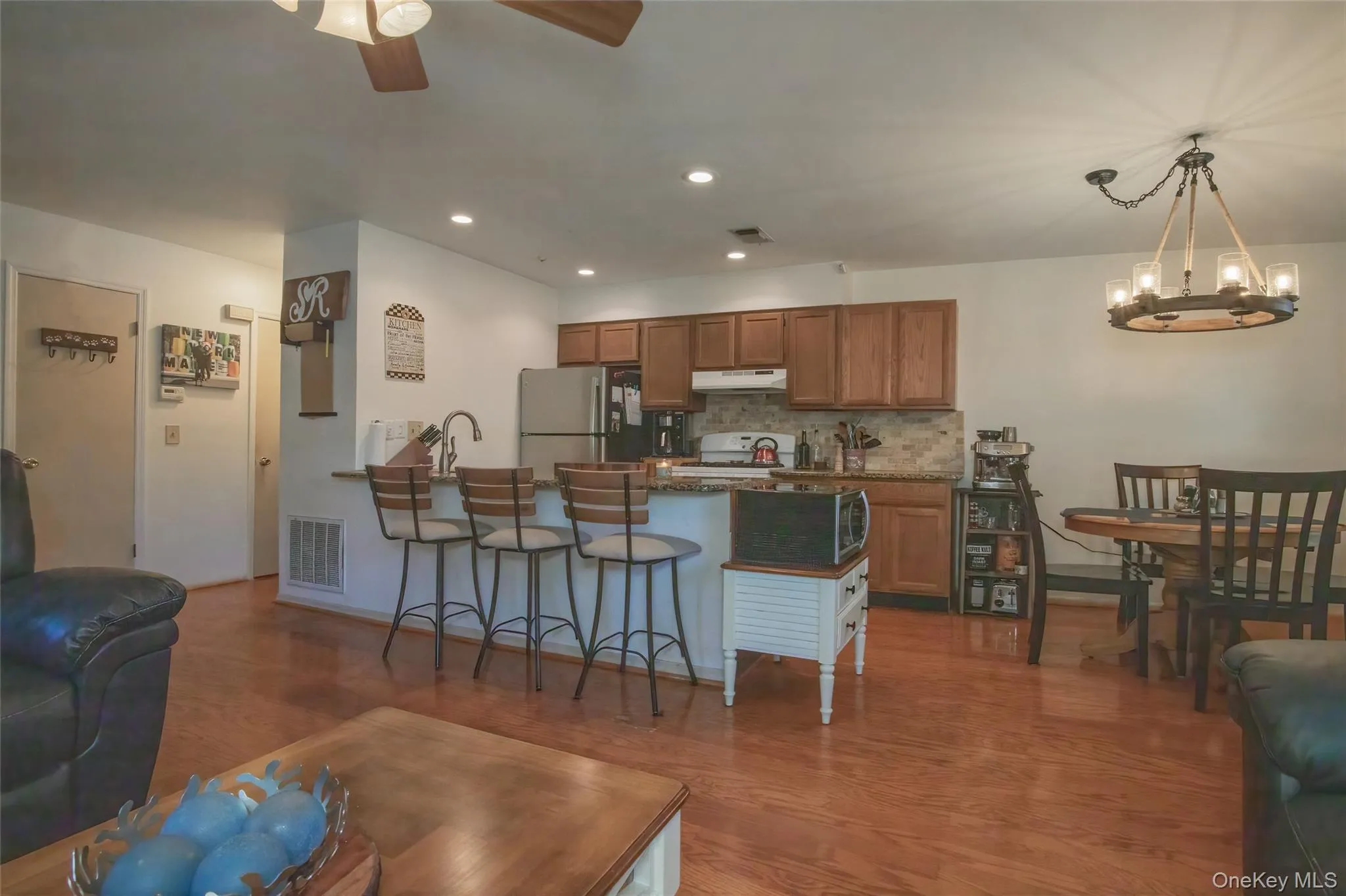 Living room with recessed lighting, light wood-style flooring, a ceiling fan, and a chandelier Living room with recessed lighting, light wood-style flooring, a ceiling fan, and a chandelier