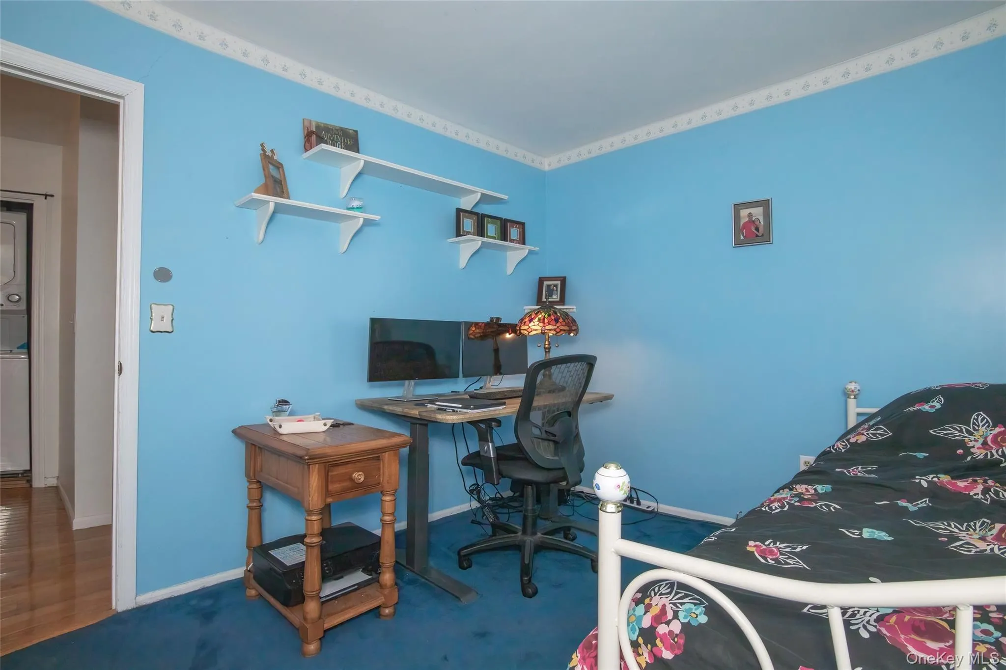 Carpeted bedroom with an office area and stacked washer / dryer Carpeted bedroom with an office area and stacked washer / dryer