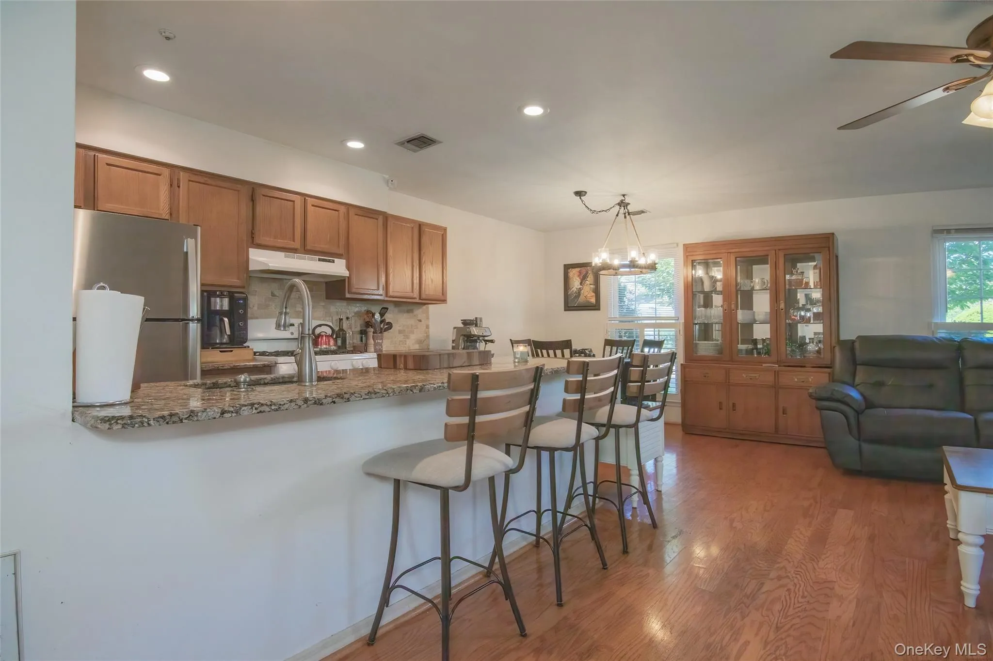 Kitchen featuring a kitchen bar, brown cabinets, freestanding refrigerator, backsplash, and pendant lighting Kitchen featuring a kitchen bar, brown cabinets, freestanding refrigerator, backsplash, and pendant lighting