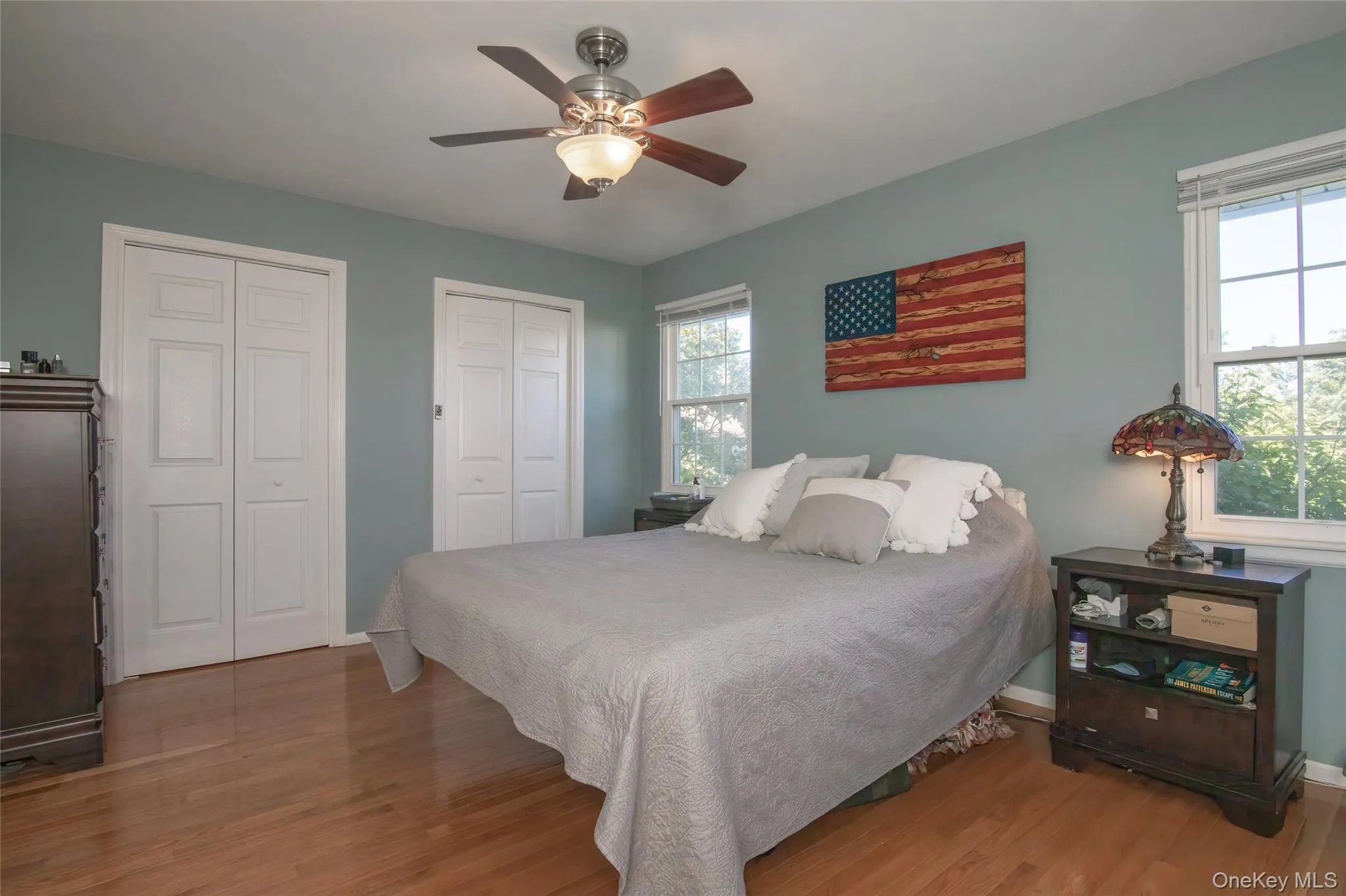 Bedroom with multiple closets, light wood-style floors, and ceiling fan Bedroom with multiple closets, light wood-style floors, and ceiling fan