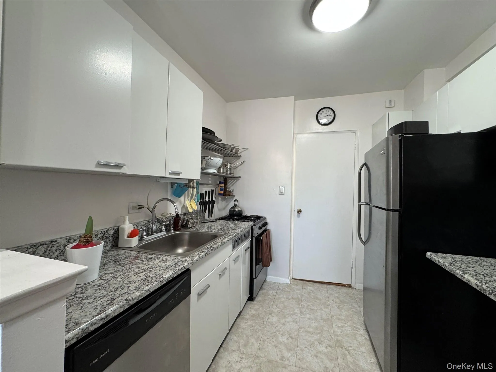 Kitchen with appliances with stainless steel finishes, white cabinets, and light stone countertops Kitchen with appliances with stainless steel finishes, white cabinets, and light stone countertops