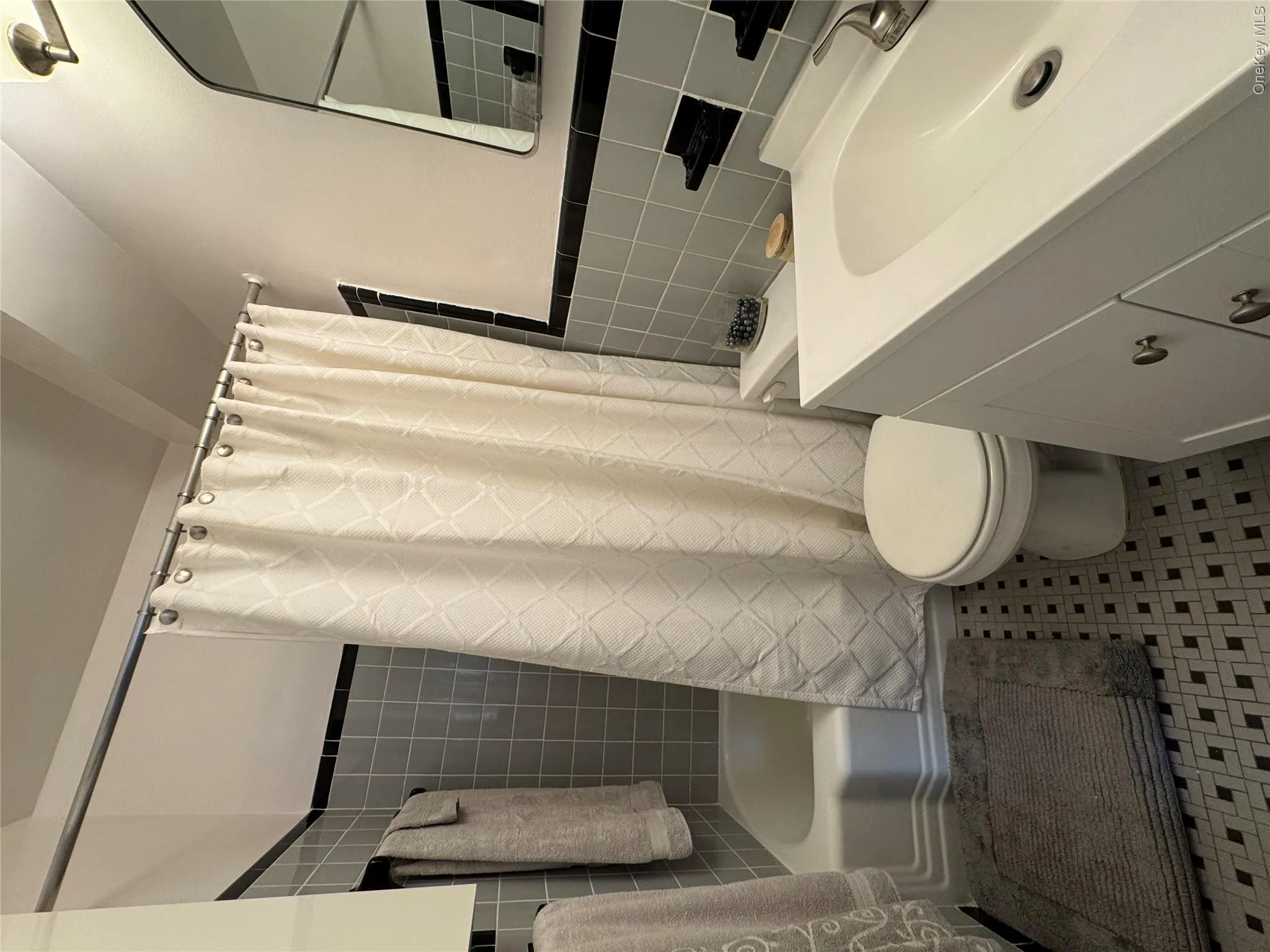 Bathroom featuring shower / bath combo, tile walls, vanity, and light tile patterned floors Bathroom featuring shower / bath combo, tile walls, vanity, and light tile patterned floors
