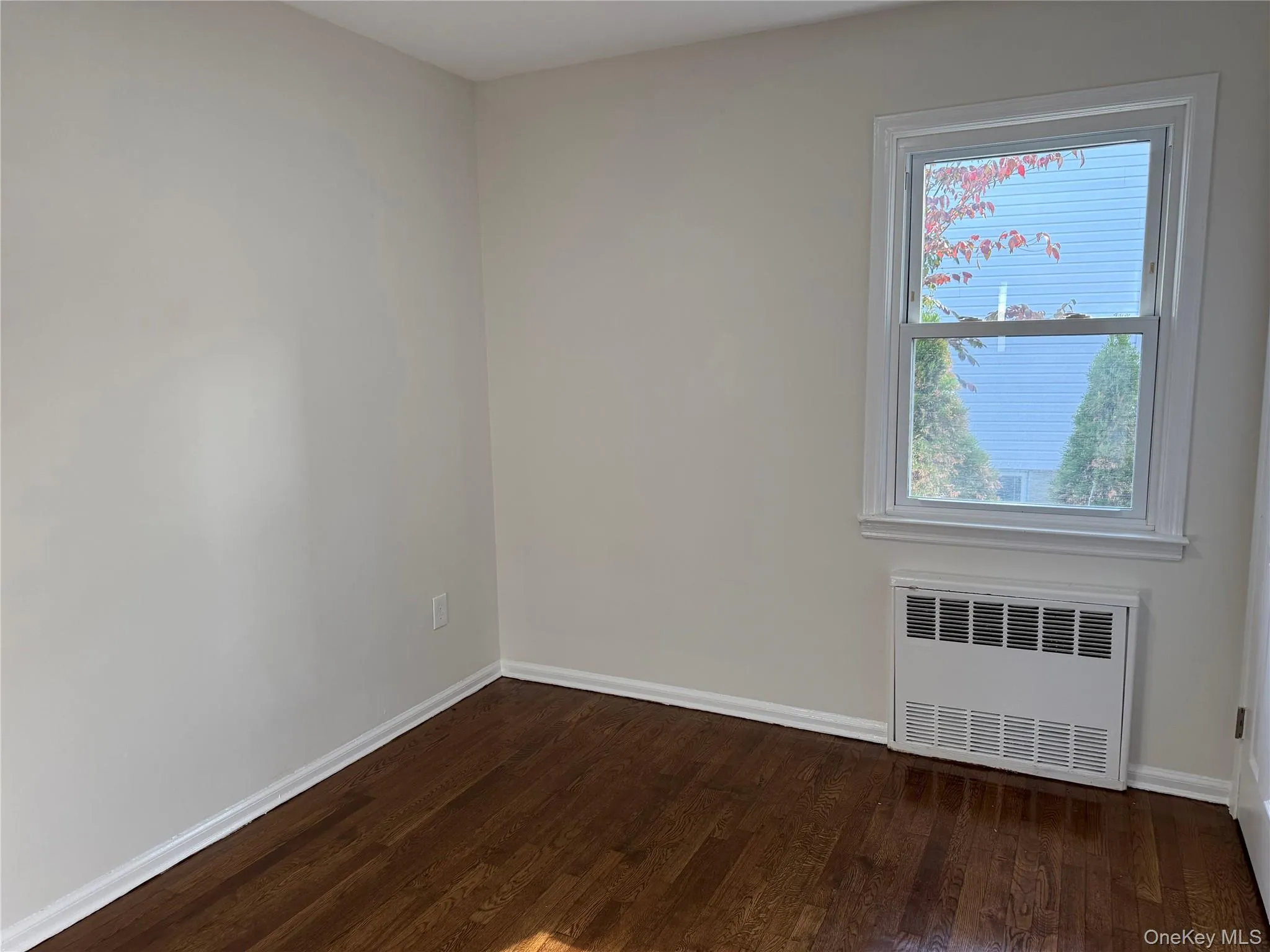 Spare room with dark wood-type flooring and radiator Spare room with dark wood-type flooring and radiator
