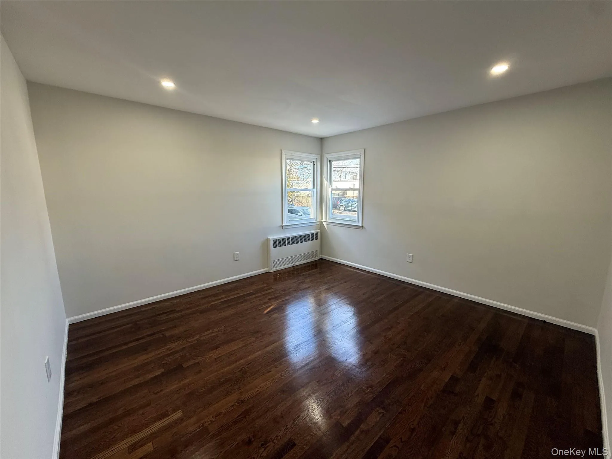 Empty room featuring dark wood finished floors, recessed lighting, and radiator Empty room featuring dark wood finished floors, recessed lighting, and radiator