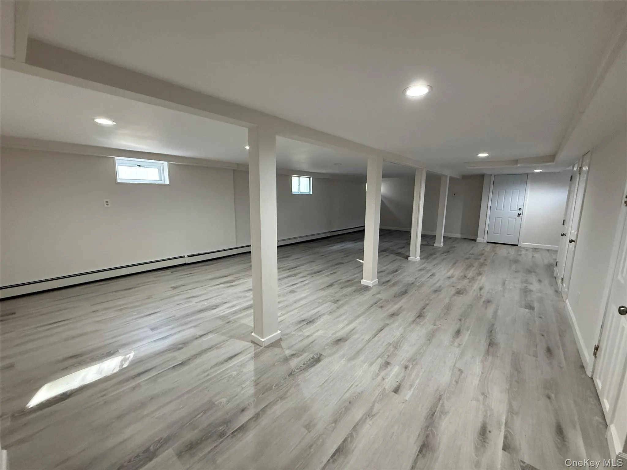 Basement with recessed lighting, a baseboard radiator, and light wood finished floors Basement with recessed lighting, a baseboard radiator, and light wood finished floors