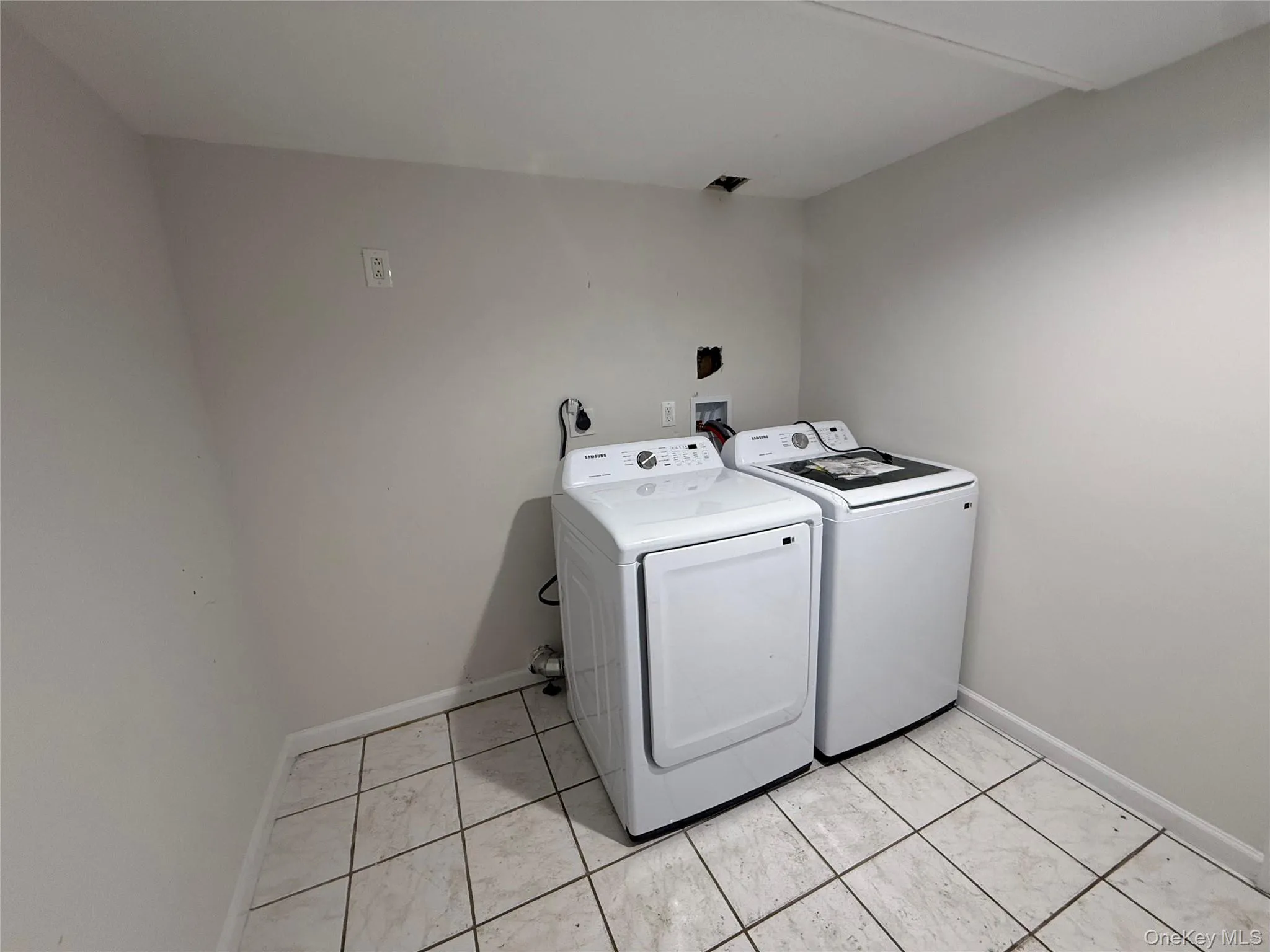 Laundry area with separate washer and dryer and light tile patterned floors Laundry area with separate washer and dryer and light tile patterned floors