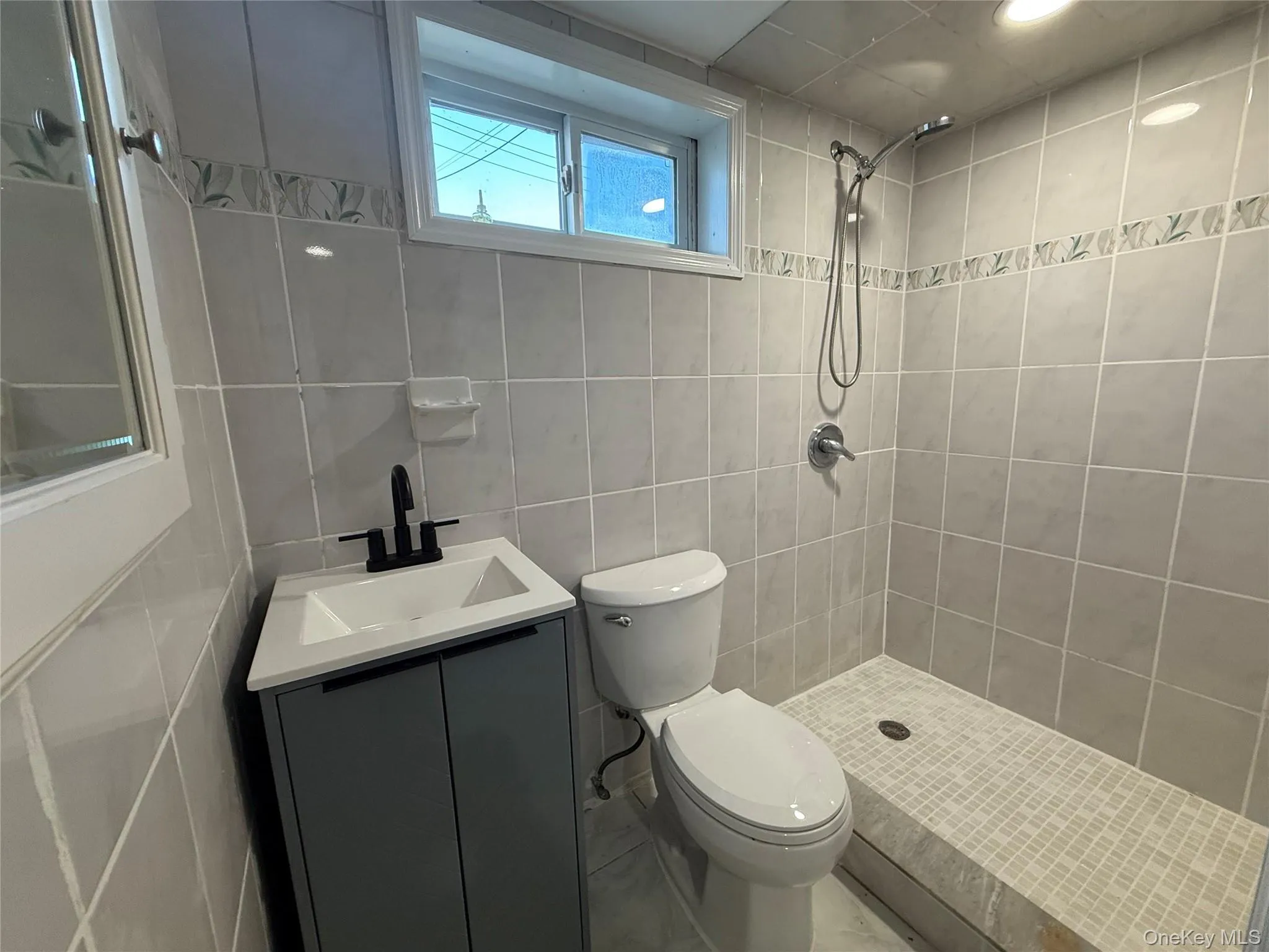 Full bath featuring a stall shower, tile walls, and vanity Full bath featuring a stall shower, tile walls, and vanity
