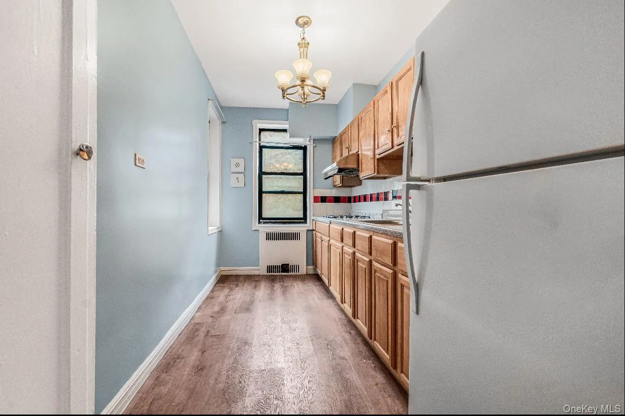 Kitchen with freestanding refrigerator, tasteful backsplash, a chandelier, light wood finished floors, and pendant lighting Kitchen with freestanding refrigerator, tasteful backsplash, a chandelier, light wood finished floors, and pendant lighting