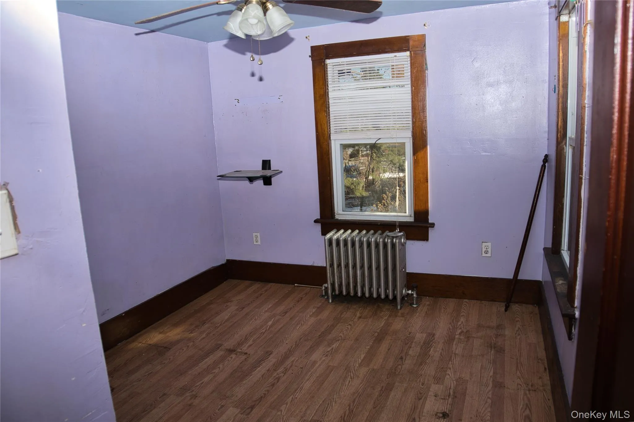 Spare room with radiator, dark wood finished floors, and a ceiling fan Spare room with radiator, dark wood finished floors, and a ceiling fan