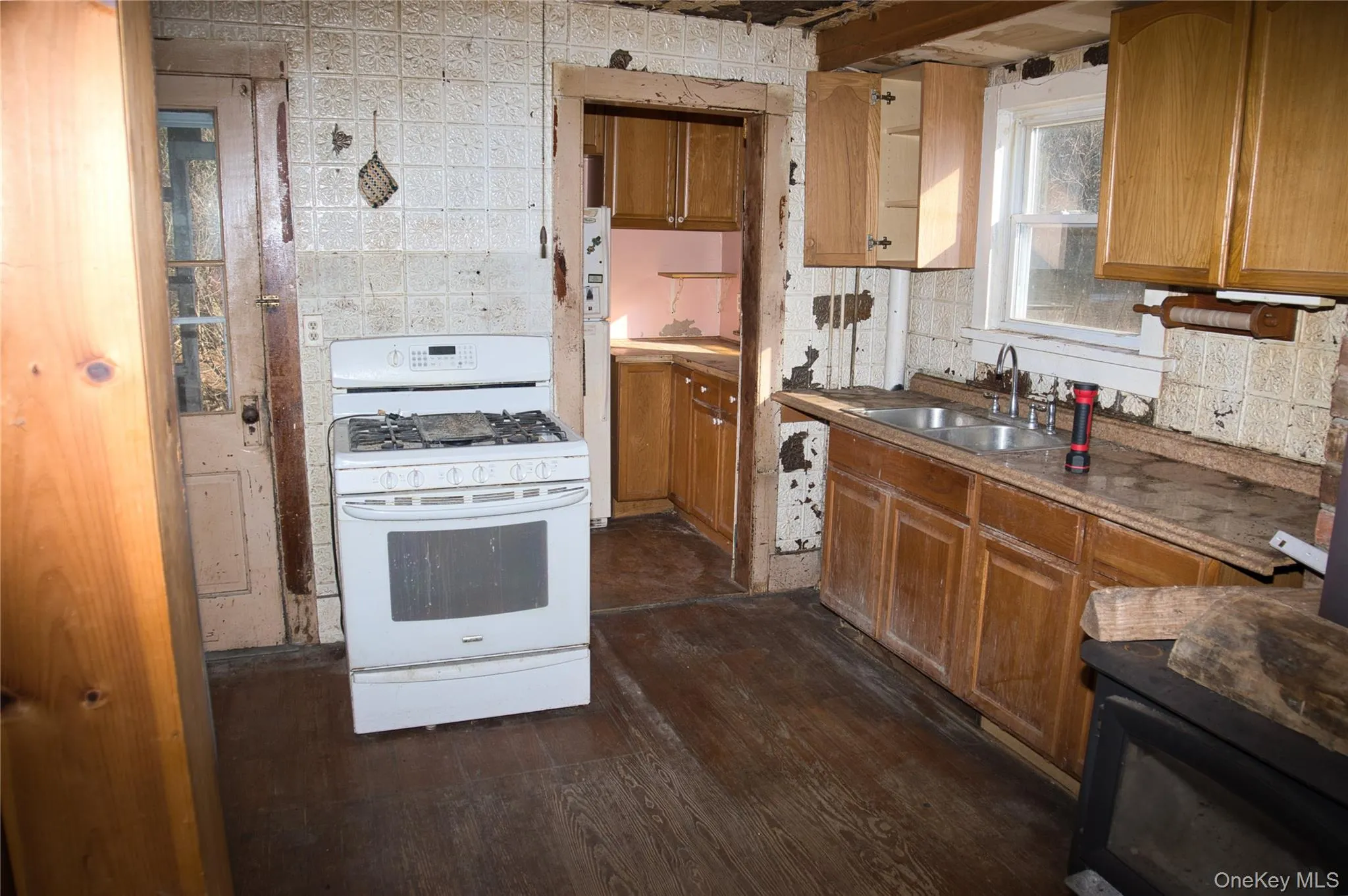 Kitchen featuring white appliances, brown cabinets, dark wood-style flooring, and tasteful backsplash Kitchen featuring white appliances, brown cabinets, dark wood-style flooring, and tasteful backsplash