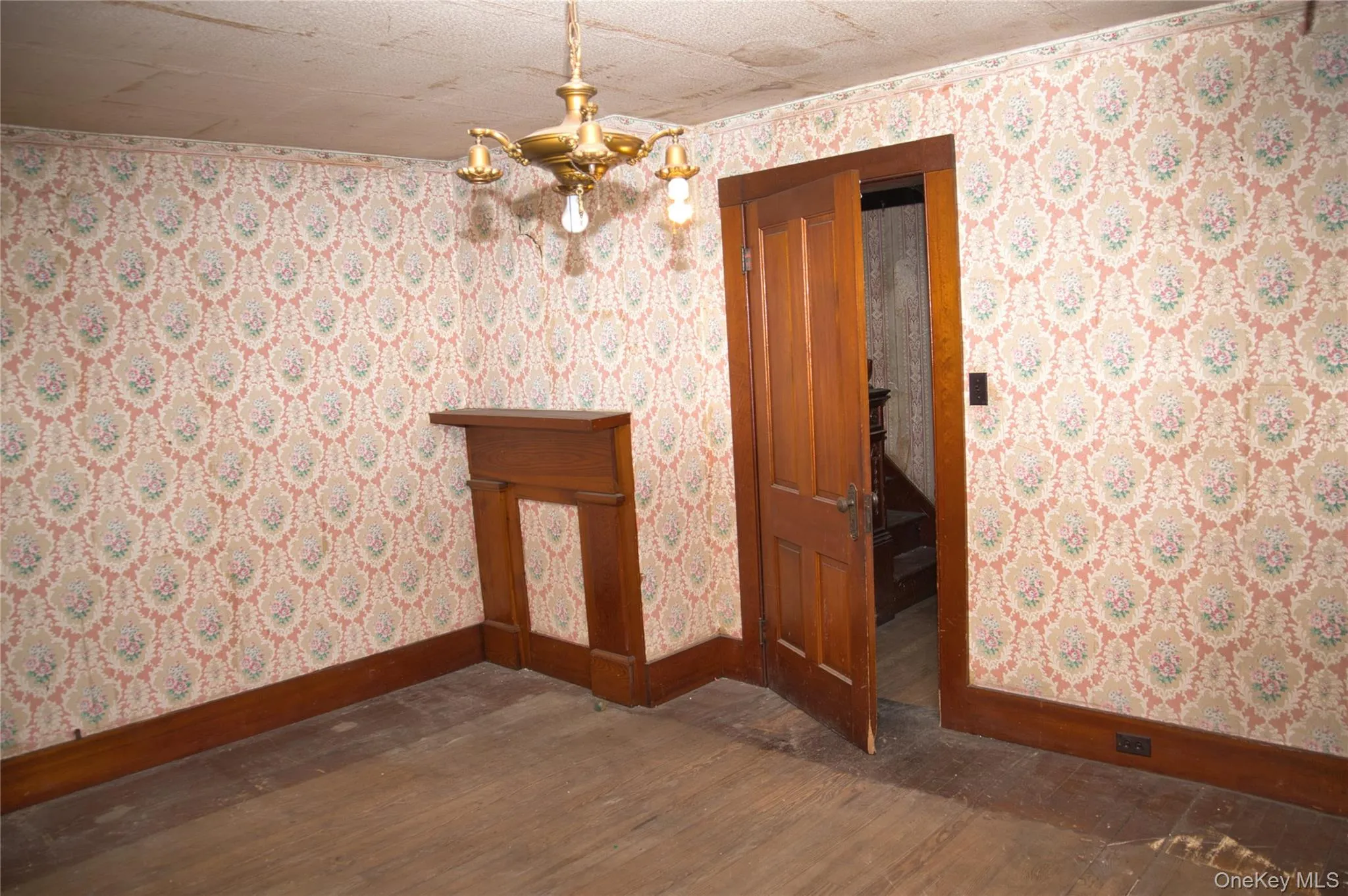 Unfurnished dining area with wallpapered walls, dark wood-style floors, and a chandelier Unfurnished dining area with wallpapered walls, dark wood-style floors, and a chandelier