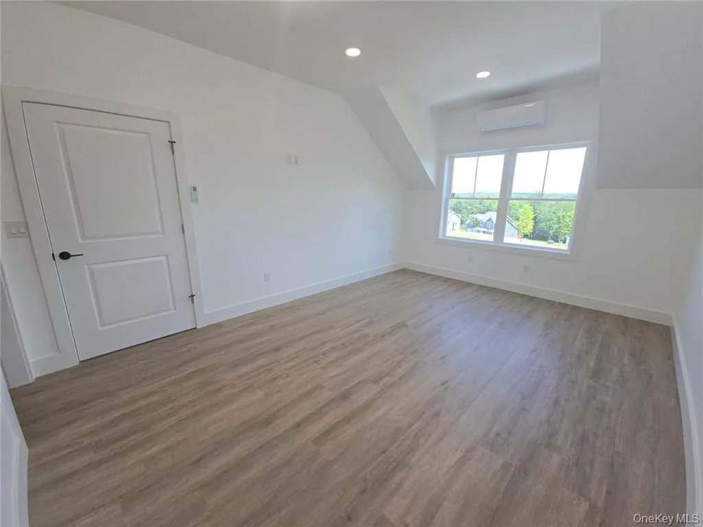 Bonus room featuring recessed lighting, wood finished floors, vaulted ceiling, and a wall unit AC Bonus room featuring recessed lighting, wood finished floors, vaulted ceiling, and a wall unit AC