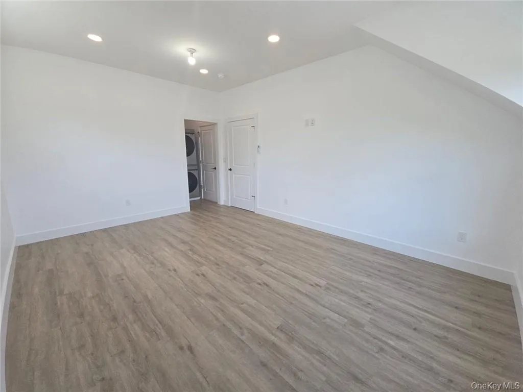 Empty room with light wood-type flooring, recessed lighting, and estacked washer and dryer Empty room with light wood-type flooring, recessed lighting, and estacked washer and dryer