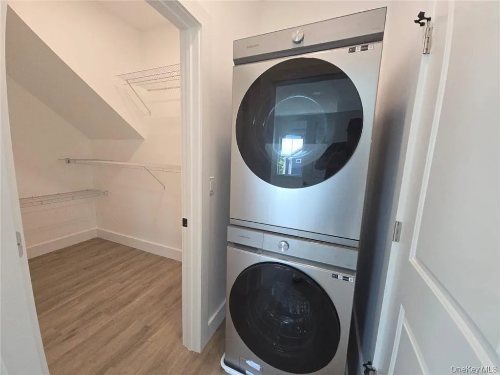 Laundry room with light wood finished floors and estacked washer and dryer Laundry room with light wood finished floors and estacked washer and dryer