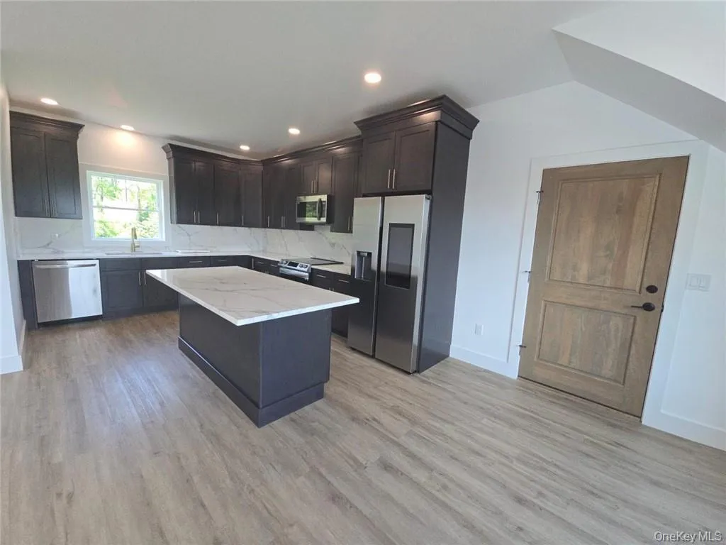 Kitchen featuring decorative backsplash, appliances with stainless steel finishes, a kitchen island, light wood finished floors, and recessed lighting Kitchen featuring decorative backsplash, appliances with stainless steel finishes, a kitchen island, light wood finished floors, and recessed lighting