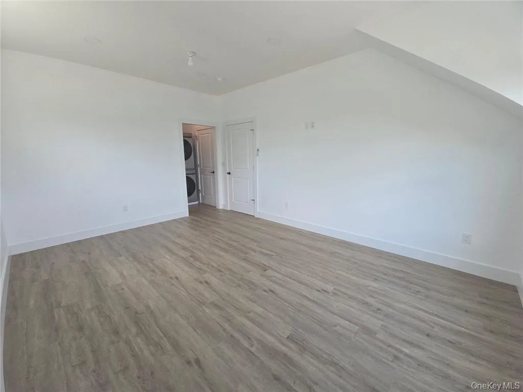 Unfurnished room with light wood-style floors and stacked washer / dryer Unfurnished room with light wood-style floors and stacked washer / dryer