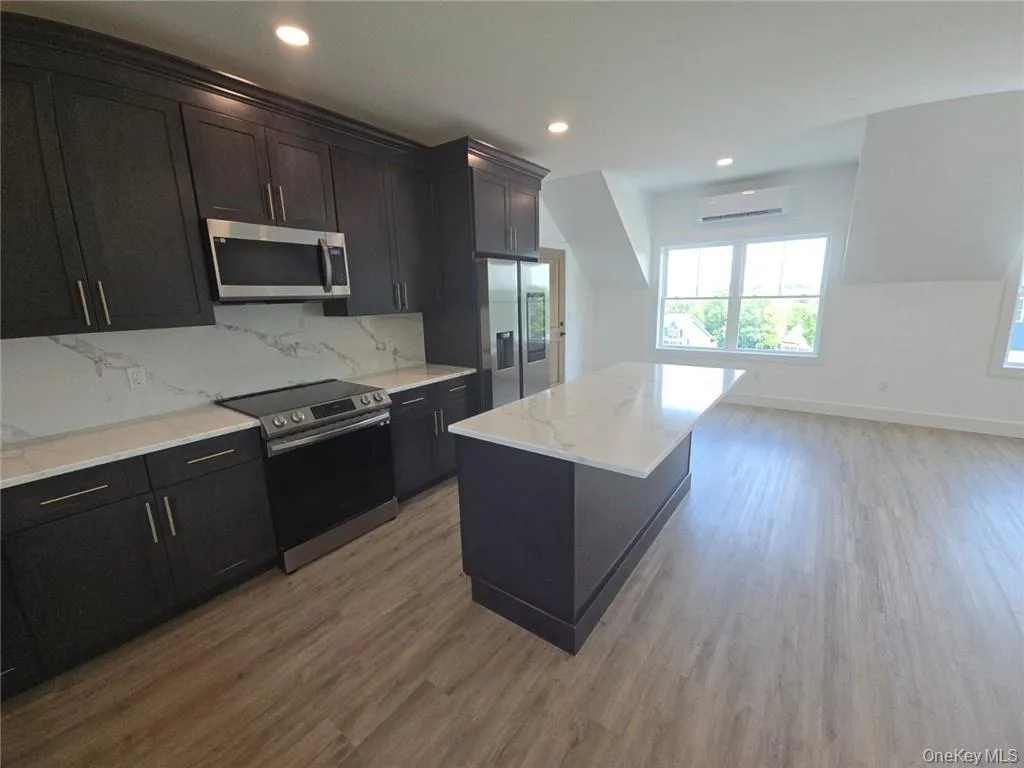 Kitchen featuring stainless steel appliances, recessed lighting, backsplash, light stone counters, and dark wood finished floors Kitchen featuring stainless steel appliances, recessed lighting, backsplash, light stone counters, and dark wood finished floors