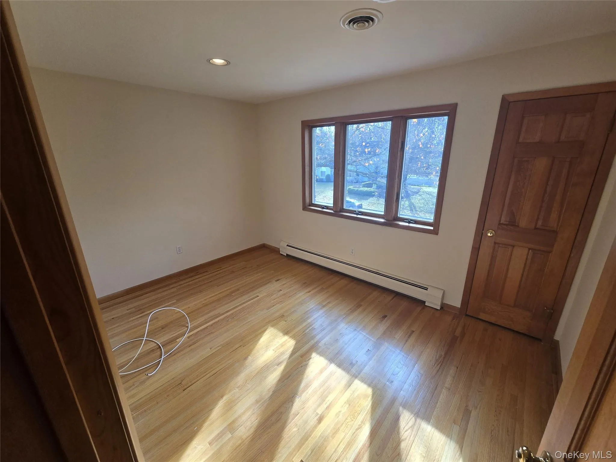 Unfurnished bedroom featuring a baseboard heating unit, light wood finished floors, and recessed lighting Unfurnished bedroom featuring a baseboard heating unit, light wood finished floors, and recessed lighting