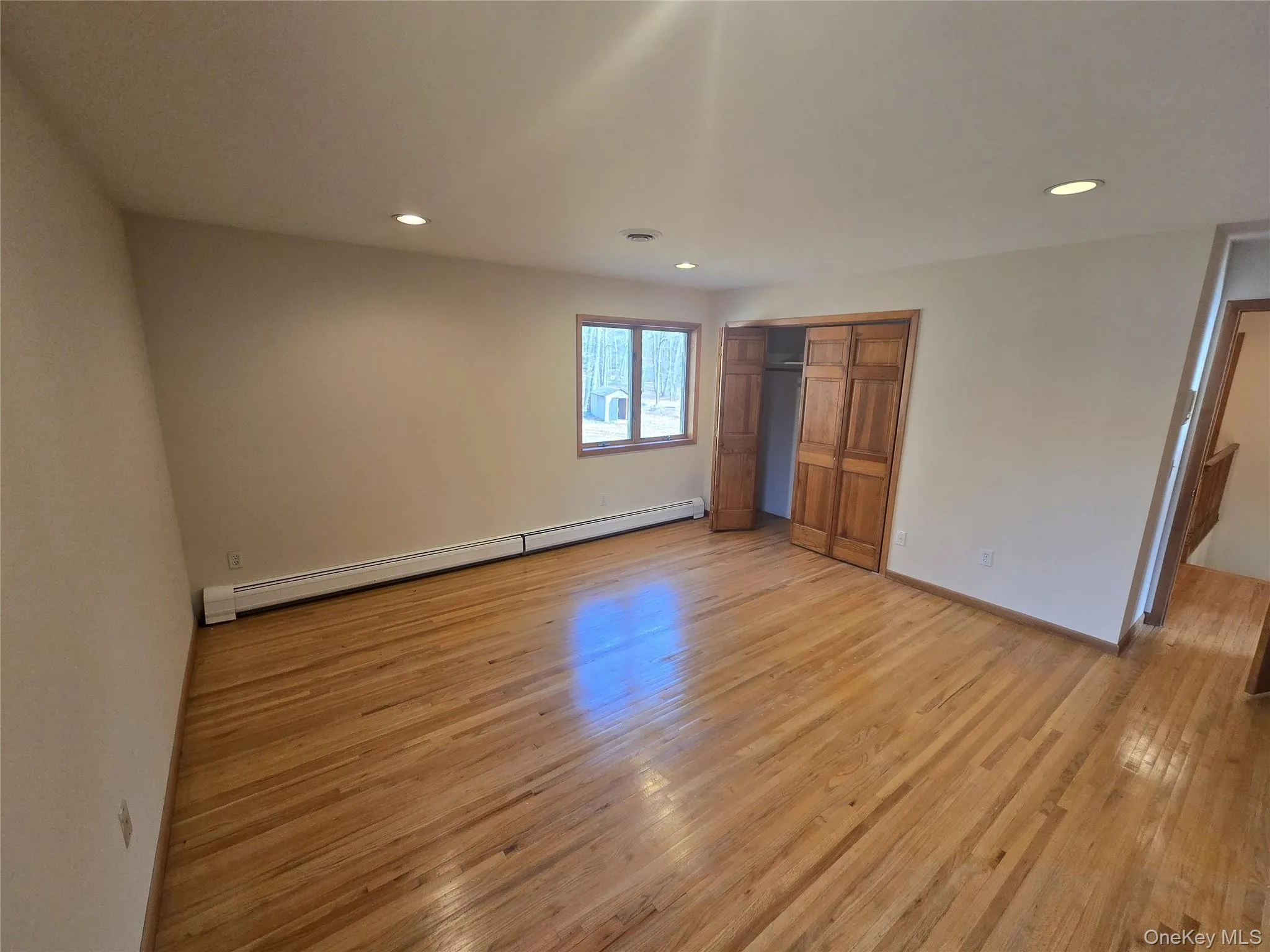 Unfurnished bedroom with a baseboard radiator, light wood-style floors, recessed lighting, and a closet Unfurnished bedroom with a baseboard radiator, light wood-style floors, recessed lighting, and a closet