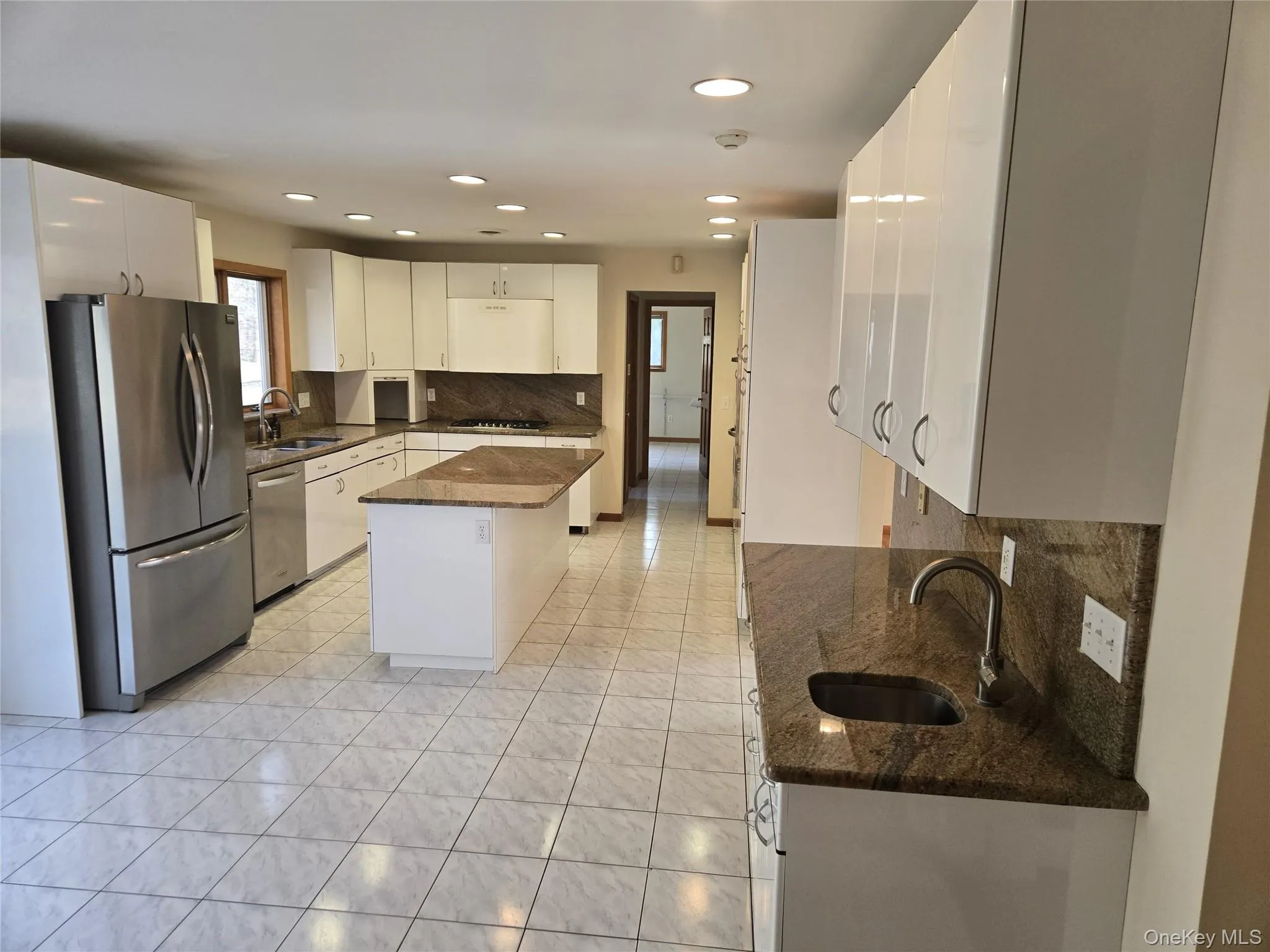 Kitchen with decorative backsplash, dark stone counters, appliances with stainless steel finishes, white cabinets, and recessed lighting Kitchen with decorative backsplash, dark stone counters, appliances with stainless steel finishes, white cabinets, and recessed lighting
