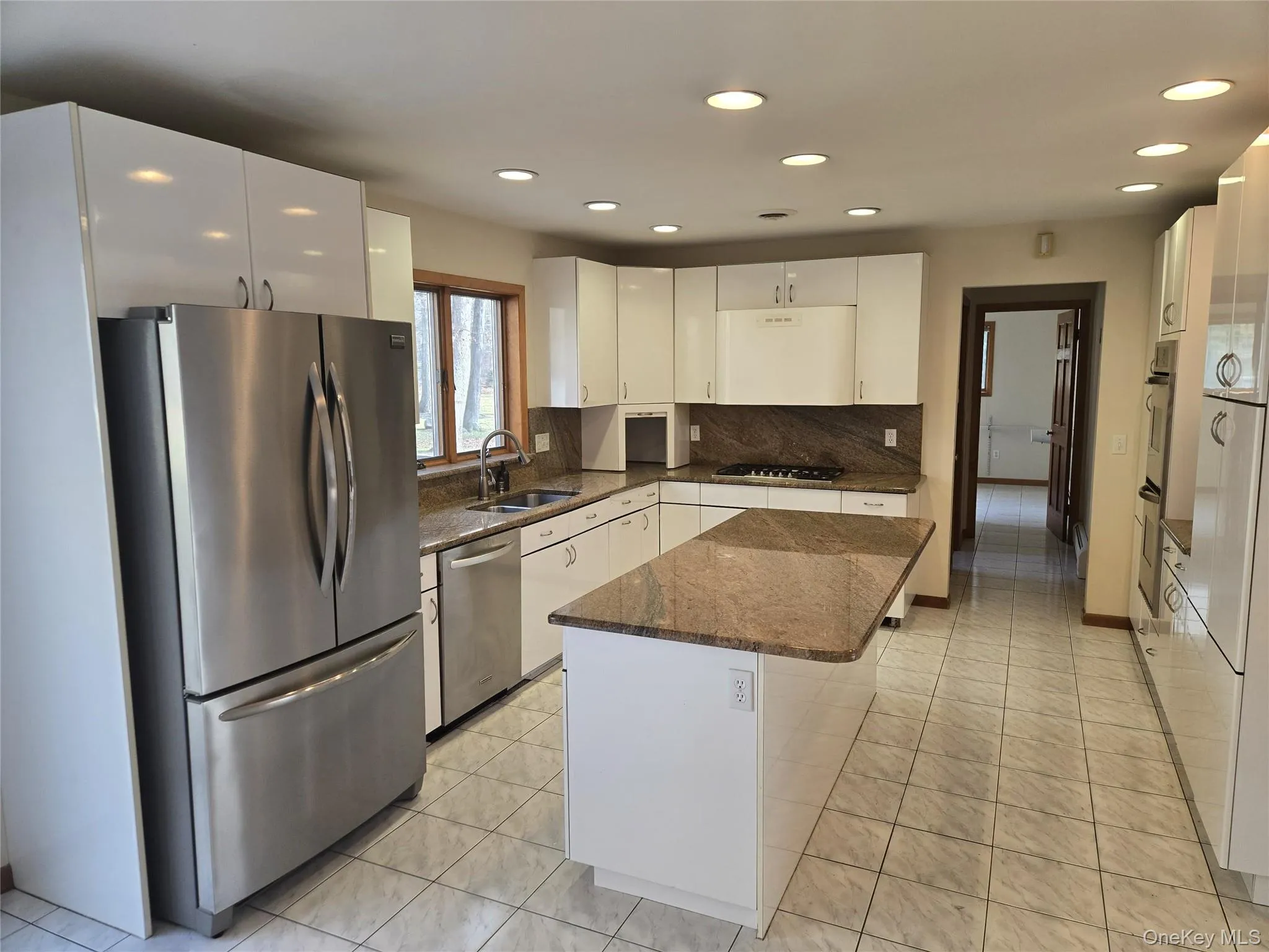 Kitchen with dark stone counters, appliances with stainless steel finishes, light tile patterned flooring, recessed lighting, and white cabinets Kitchen with dark stone counters, appliances with stainless steel finishes, light tile patterned flooring, recessed lighting, and white cabinets