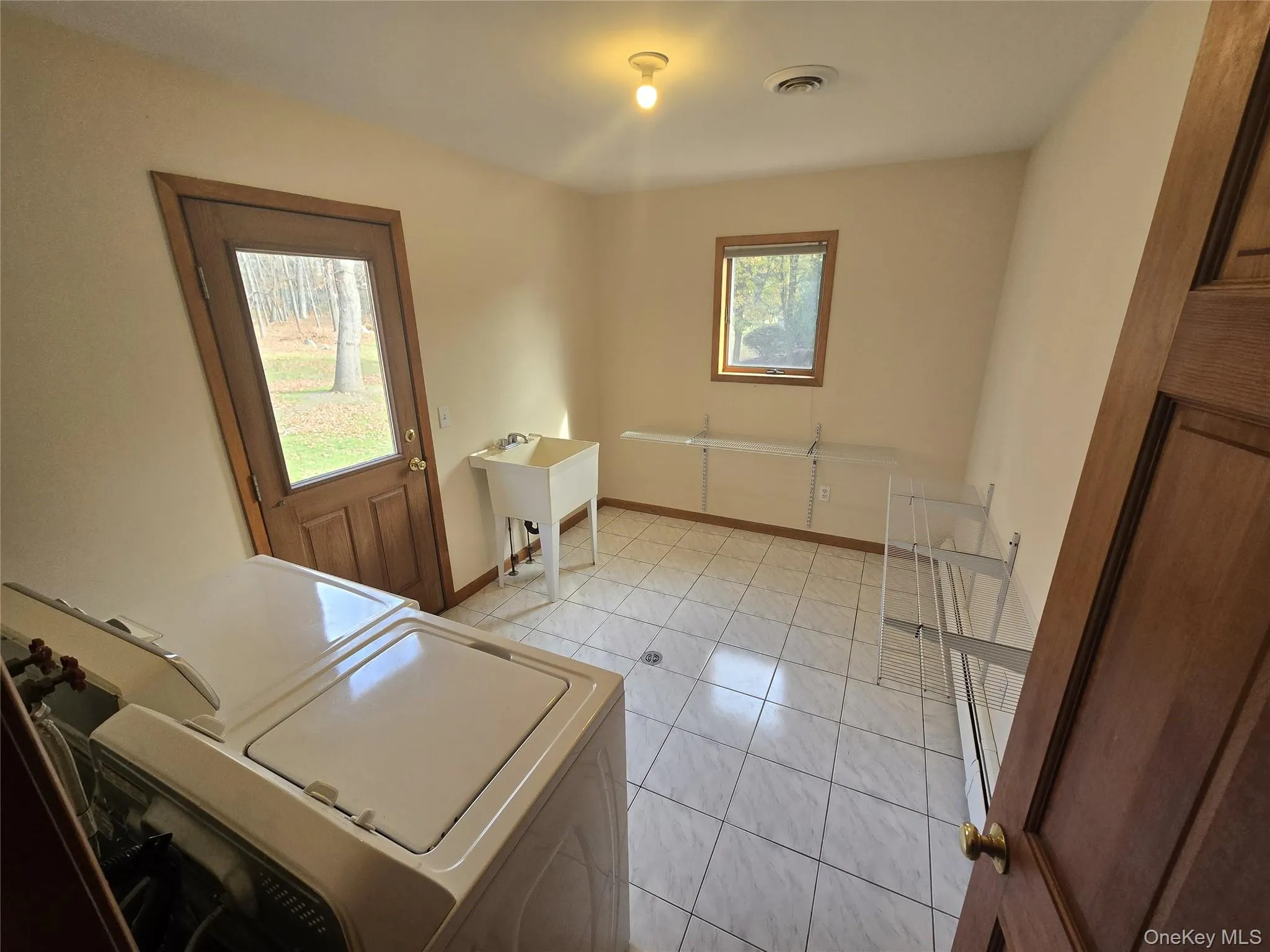 Laundry room featuring light tile patterned floors and independent washer and dryer Laundry room featuring light tile patterned floors and independent washer and dryer