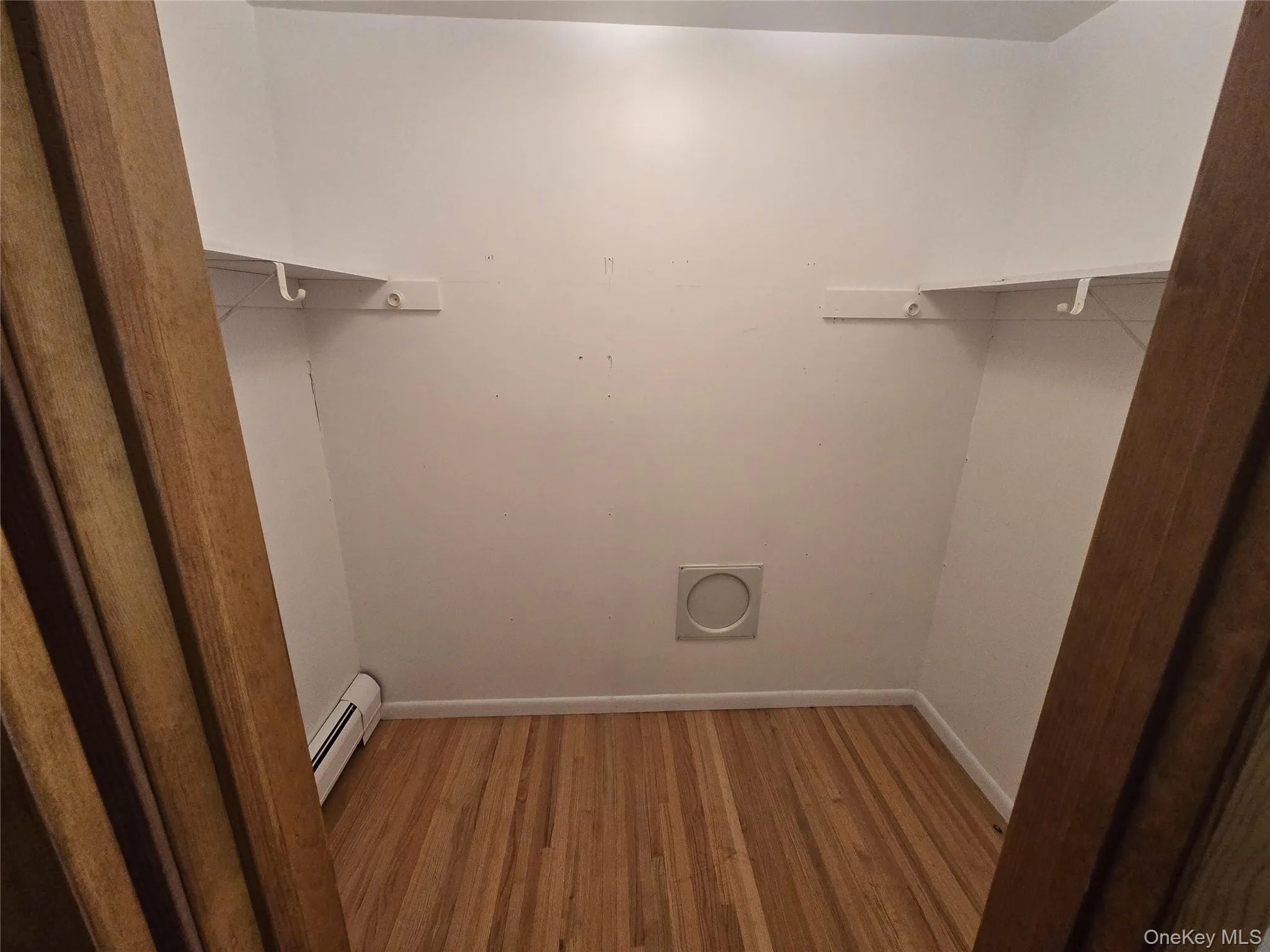 Spacious closet featuring light wood finished floors and a baseboard radiator Spacious closet featuring light wood finished floors and a baseboard radiator