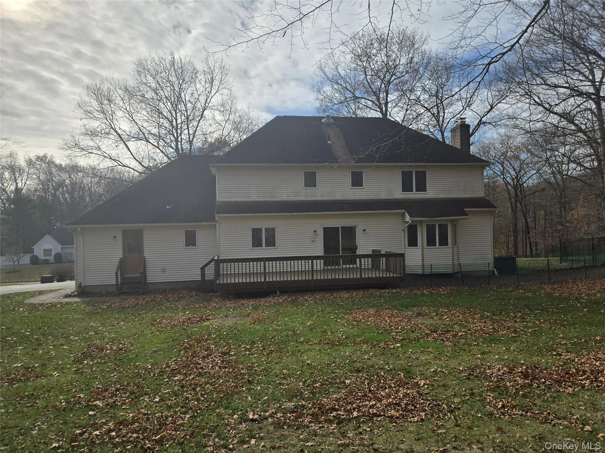 Rear view of property featuring a chimney, a yard, and a deck Rear view of property featuring a chimney, a yard, and a deck
