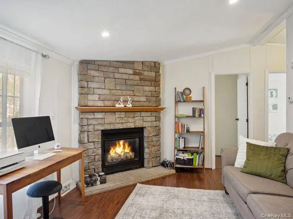 Living room featuring ornamental molding, dark wood finished floors, a fireplace, an office area, and recessed lighting Living room featuring ornamental molding, dark wood finished floors, a fireplace, an office area, and recessed lighting
