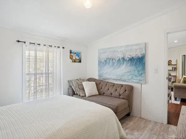 Bedroom featuring ornamental molding, wood finished floors, and vaulted ceiling Bedroom featuring ornamental molding, wood finished floors, and vaulted ceiling
