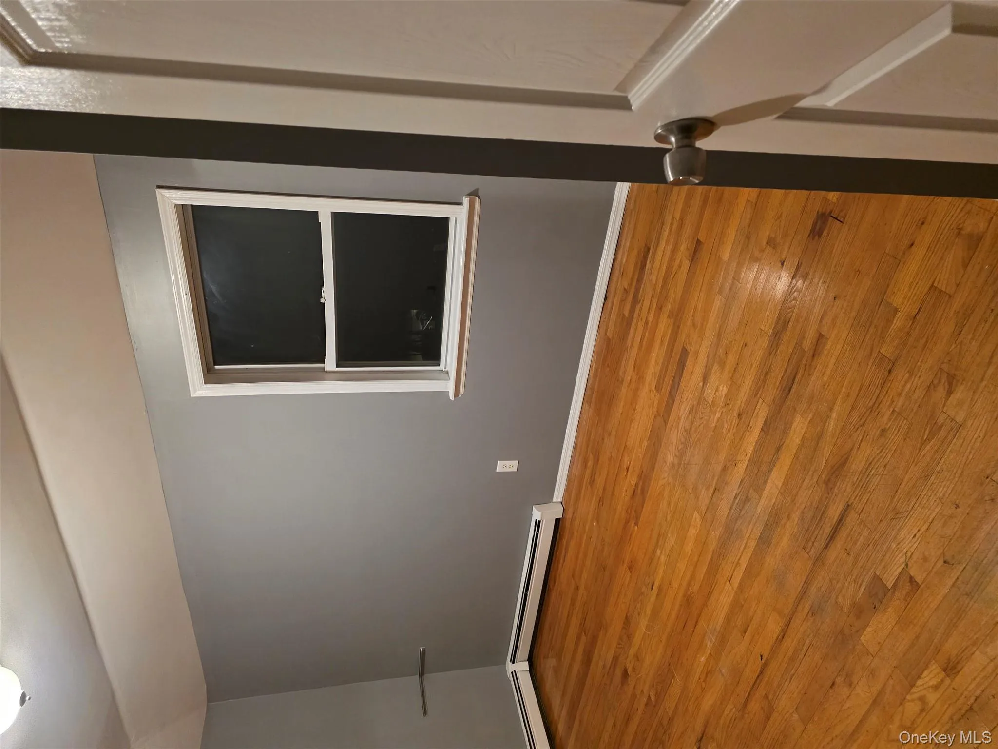 Spare room with light wood-style floors, vaulted ceiling, and a baseboard heating unit Spare room with light wood-style floors, vaulted ceiling, and a baseboard heating unit