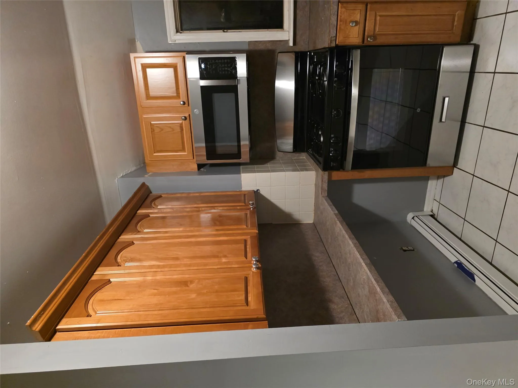 Kitchen featuring a baseboard heating unit, range, black microwave, decorative backsplash, and dark countertops Kitchen featuring a baseboard heating unit, range, black microwave, decorative backsplash, and dark countertops